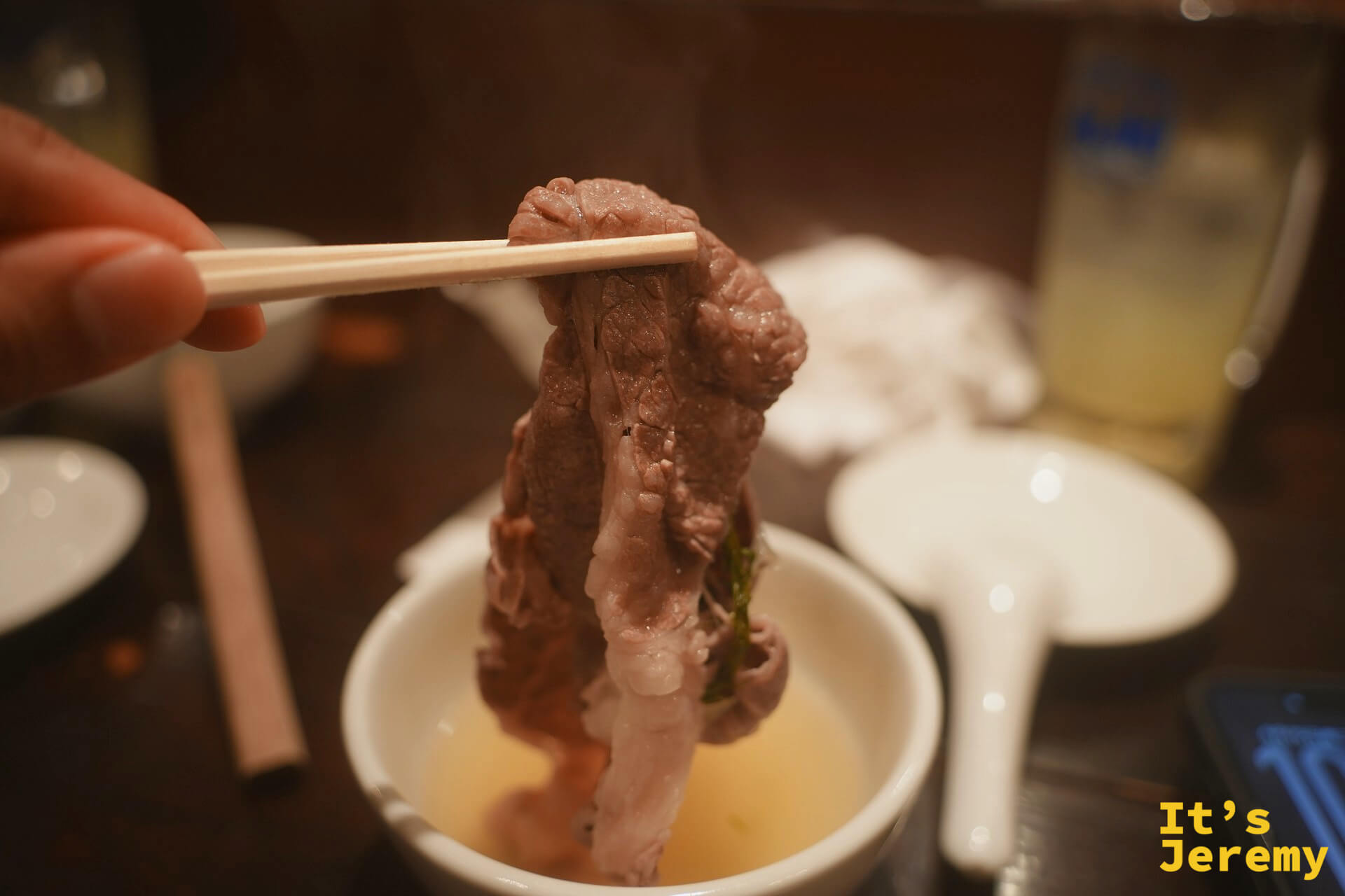 用筷子夾起涮好的和牛，從清澈的柚子高湯中取出