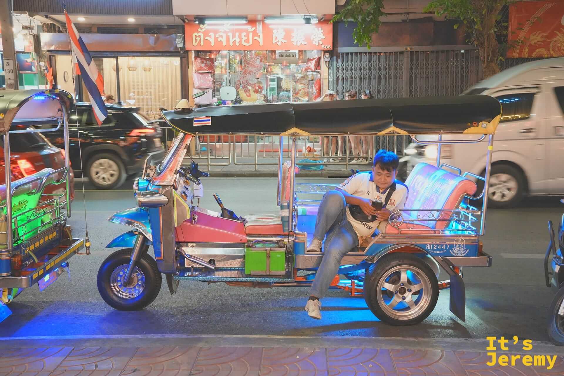側躺在嘟嘟車上滑手機等客人的嘟嘟車司機