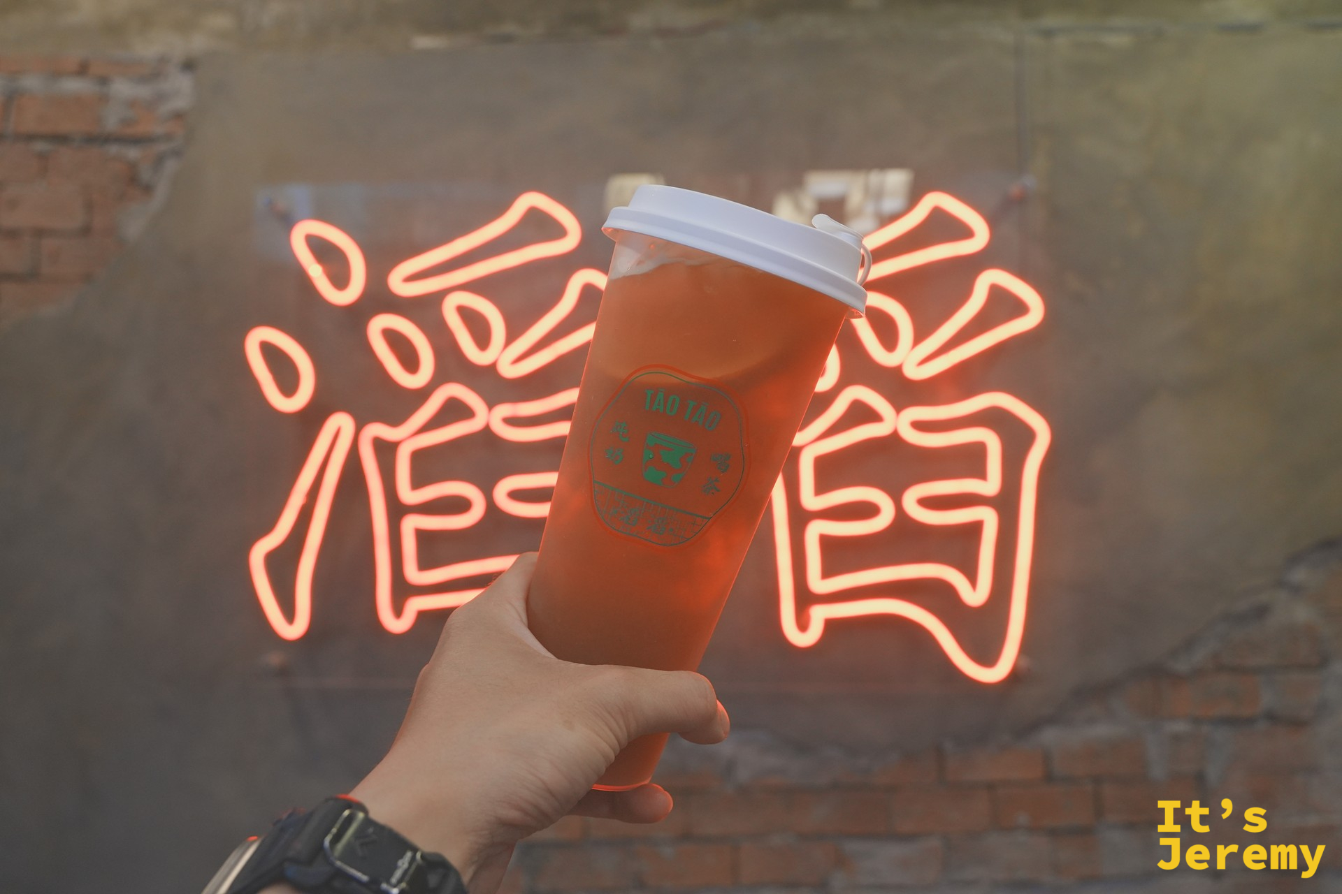 荔枝冰茶與背景的滔滔燈牌合影，店內復古色調與冰茶剛好成對比