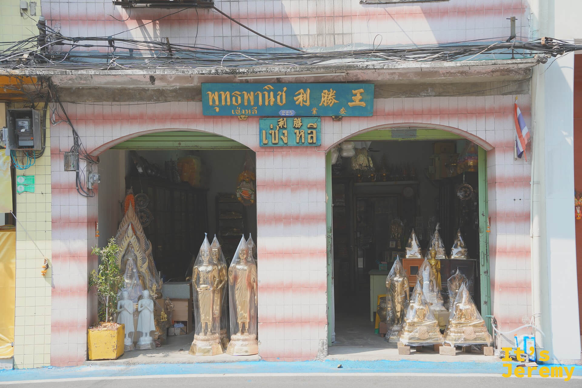 粉紅白條紋外牆的佛具店「พุทธพาณิช 利勝王」，這條街上隨處可見的中泰雙語招牌