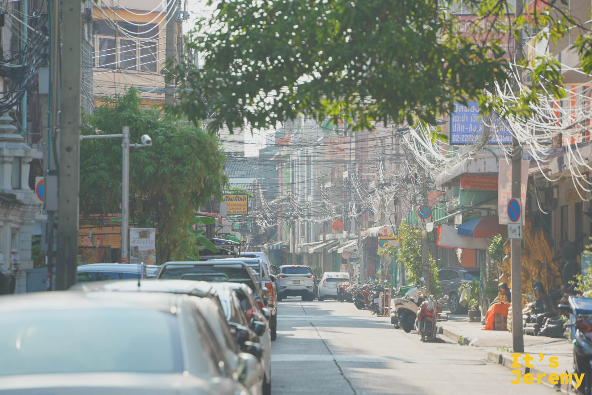傍晚老巷停滿車的住宅段，糾結電線把光線切成幾條金色直條