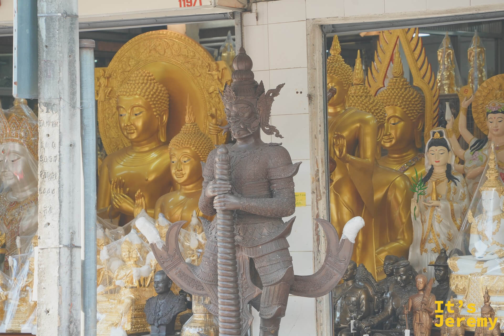 另一家佛具店的青銅戰神塑像，背景是一整面金色佛像