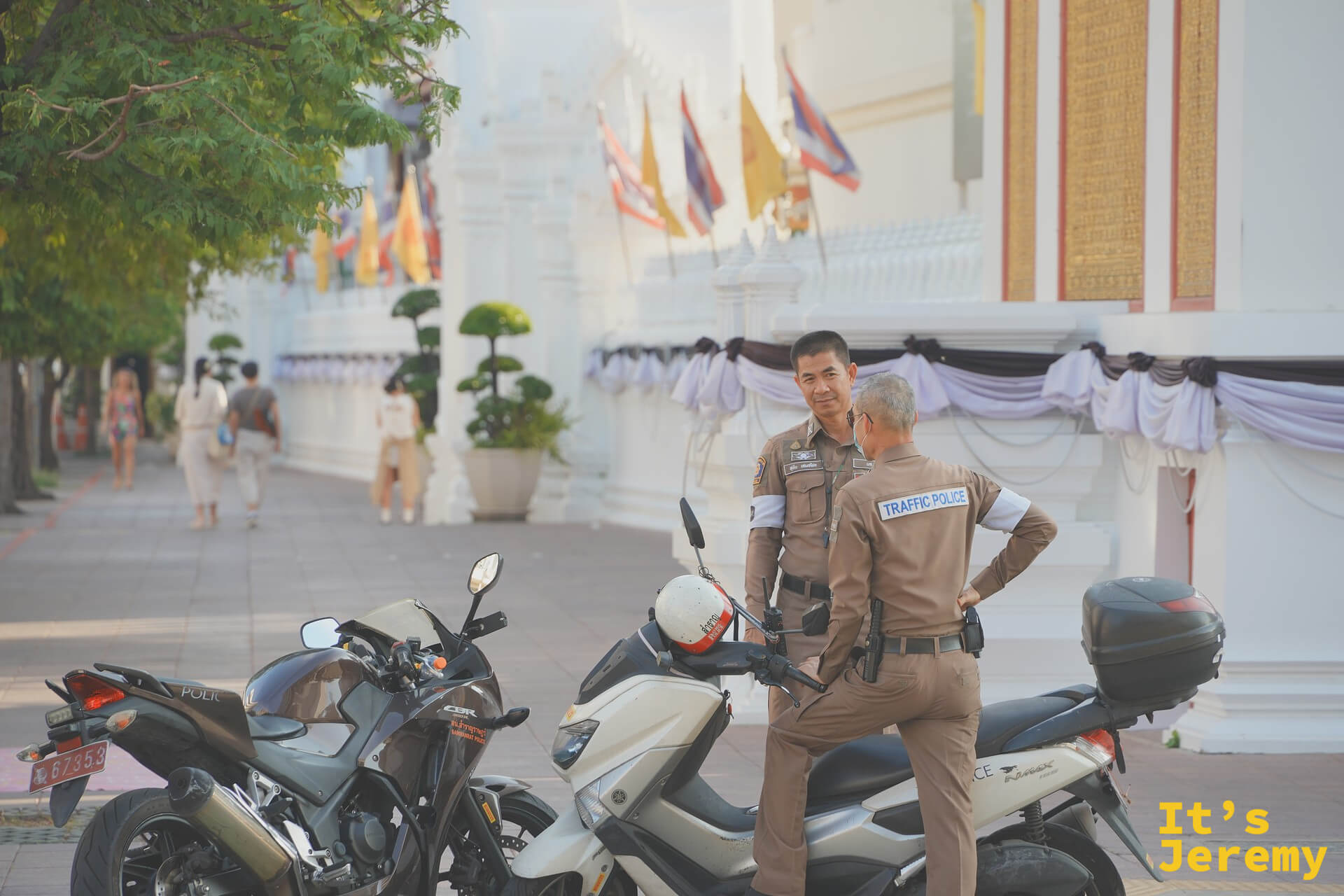 兩位 Traffic Police 觀光警察靠著機車閒聊，Wat Pho 外牆段的標準畫面