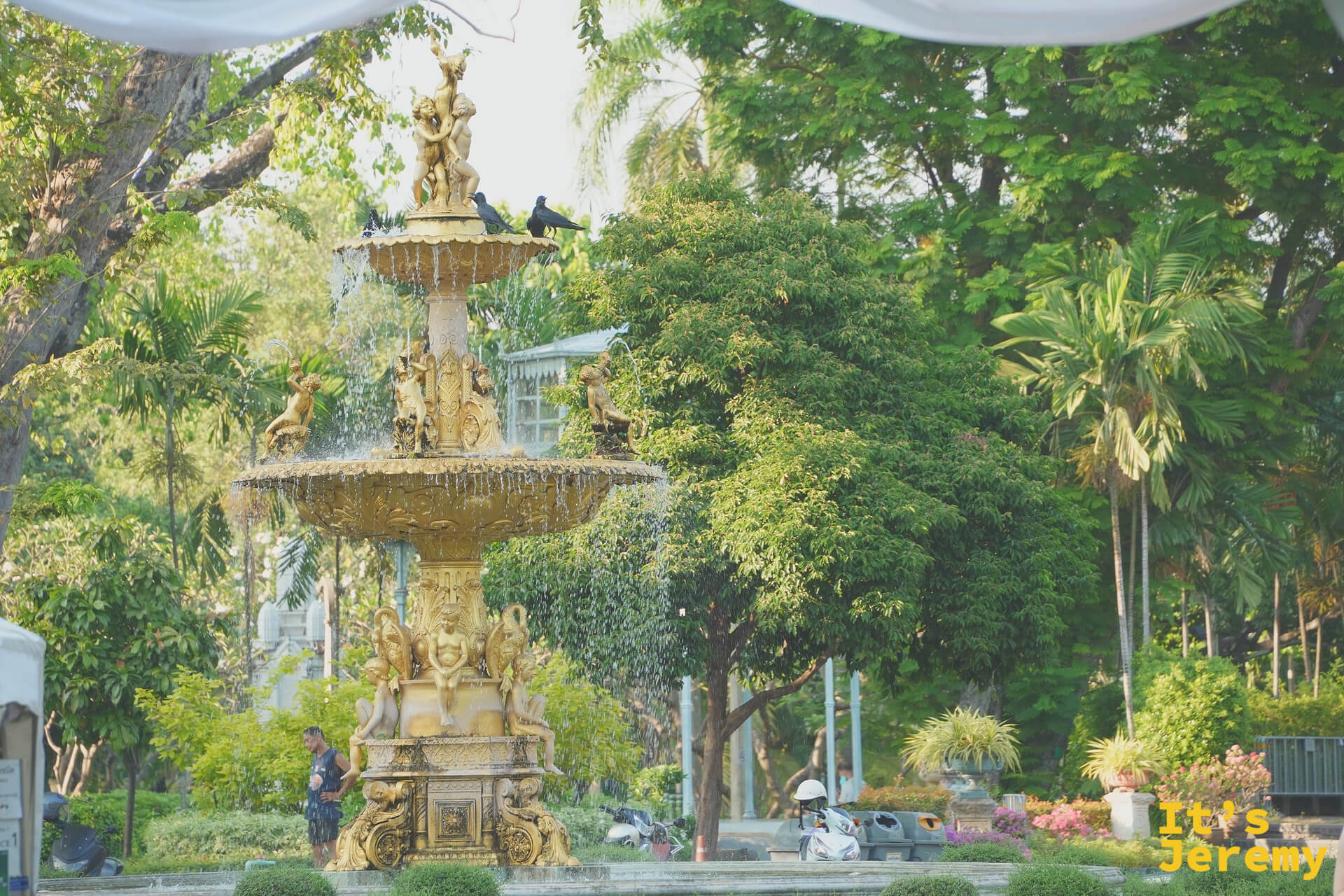 Saranrom Royal Garden 內的 1880 年代金色噴泉，灰色雕花石材在傍晚光裡帶著綠苔氣味