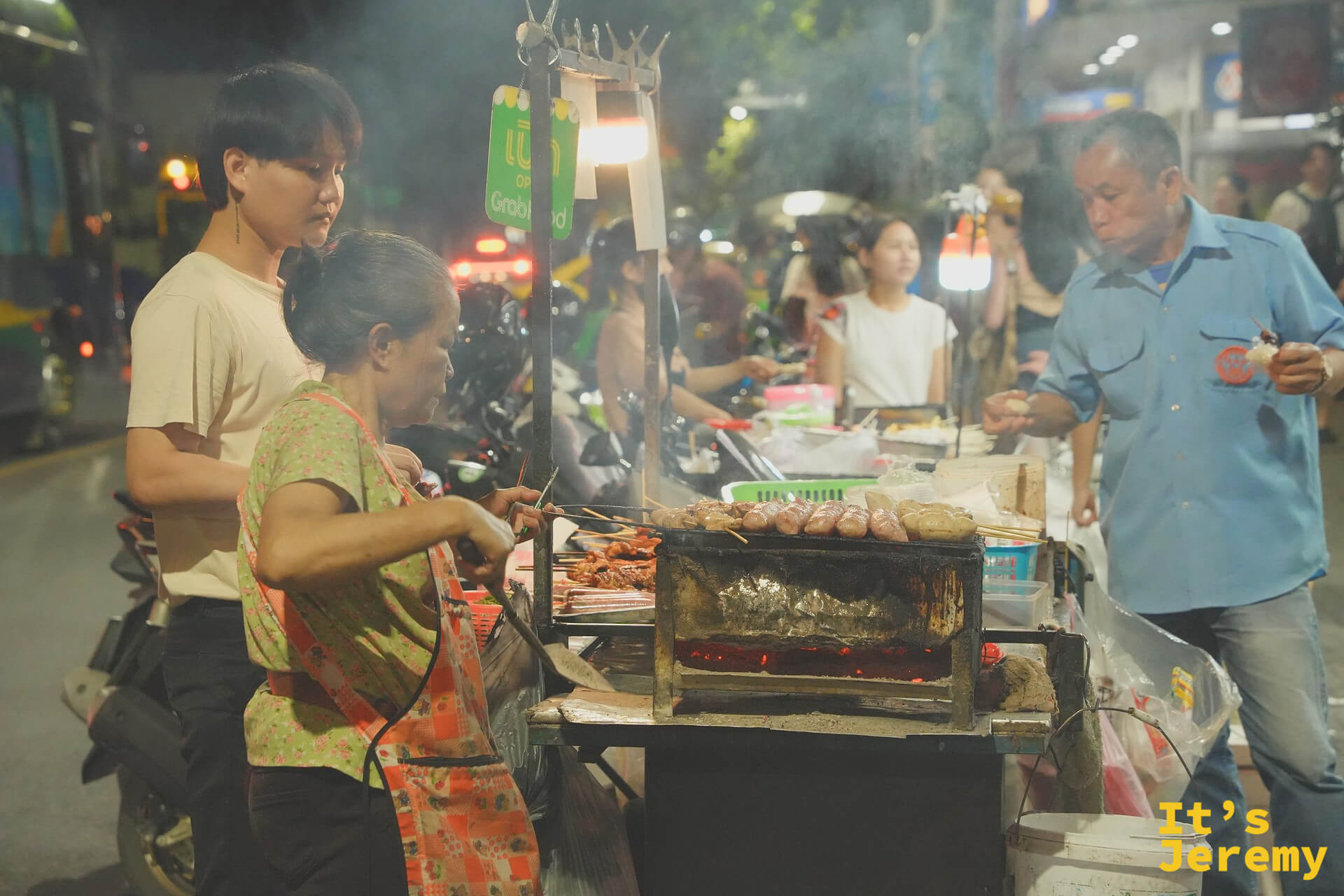 Tha Tien 街邊的炭烤老攤夜景，Grab Food 綠色招牌掛在頭頂上，傳統與外送平台的並存