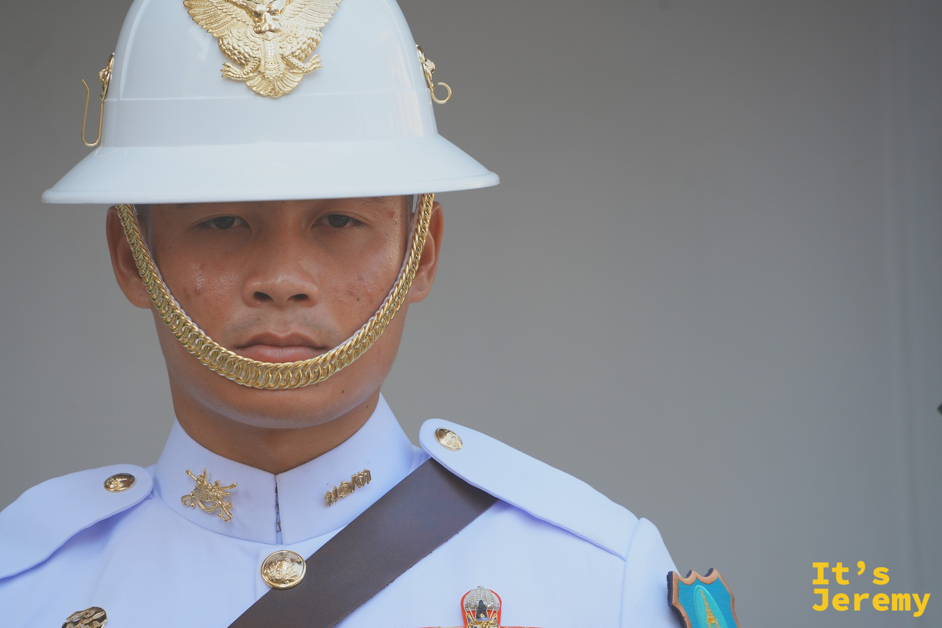 皇家衛兵正面特寫：白色制服、白色頭盔上的金色 Garuda 徽章、金鏈下顎帶