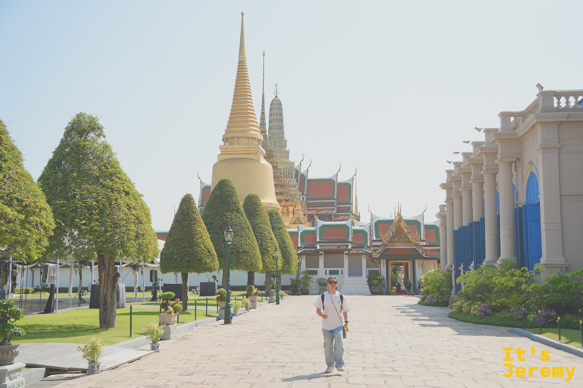 園區中軸步道上的旅人剪影，背後是金色 Phra Si Rattana Chedi 與中軸線建築群