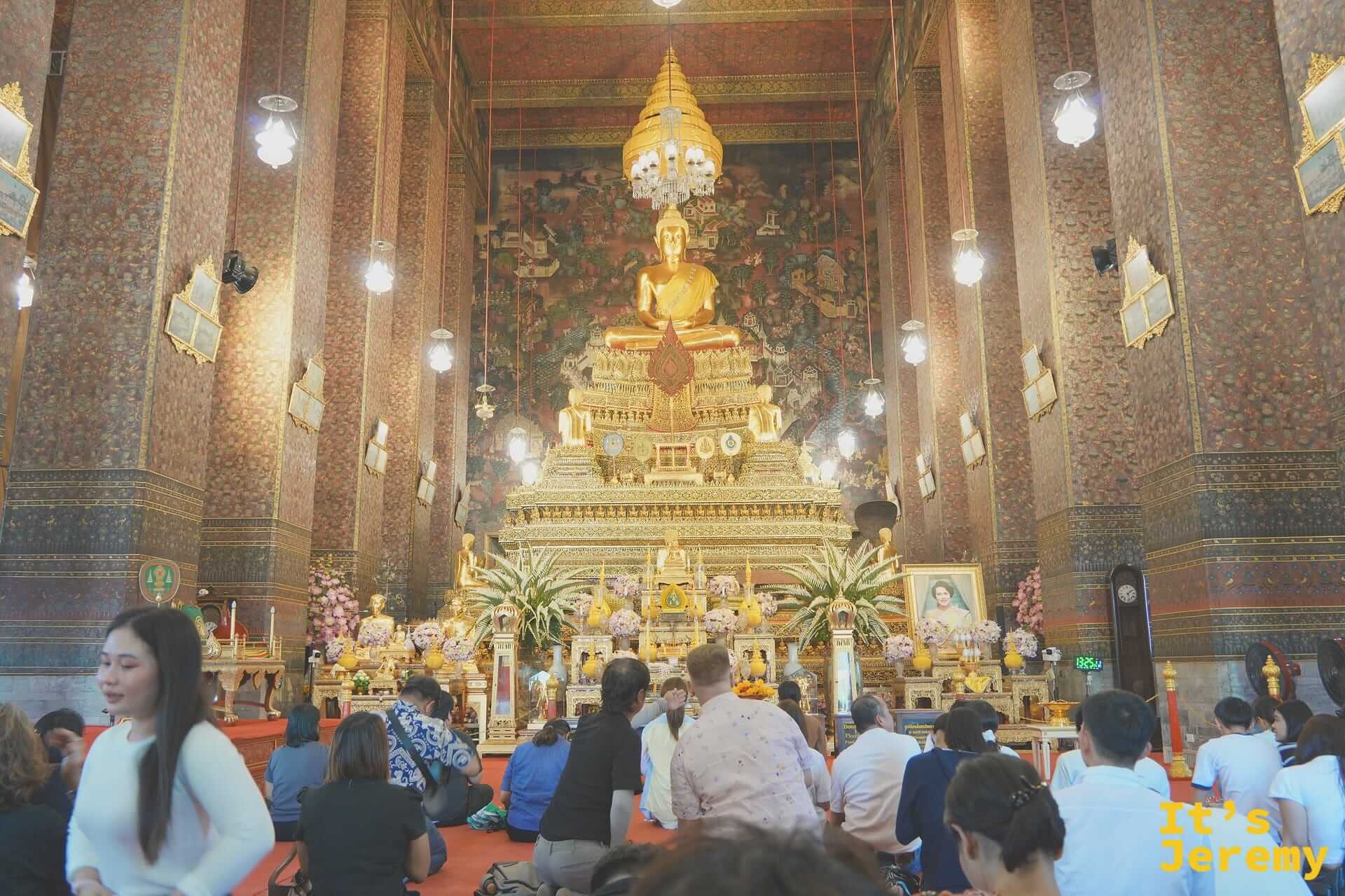 主殿內部全景，金色坐佛 Phra Buddha Deva Patimakorn 高坐台座，信徒跪地禮佛