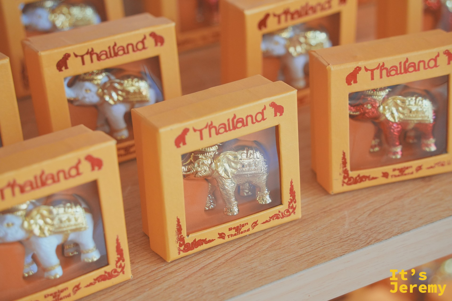 整排「Thailand」字樣的金象紀念盒，紅色泰式邊框