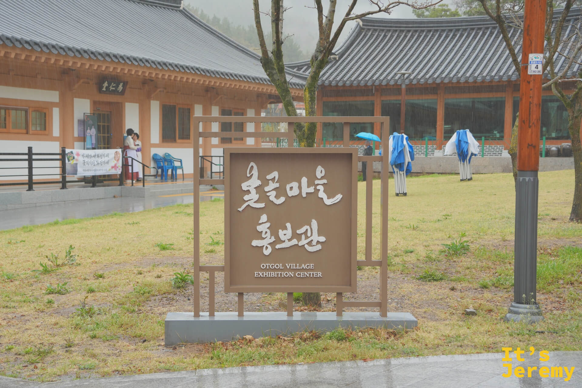 옻골마을홍보관（展覽館）入口，招牌後方是雨中的傳統韓屋，遠處可見馬造型裝置