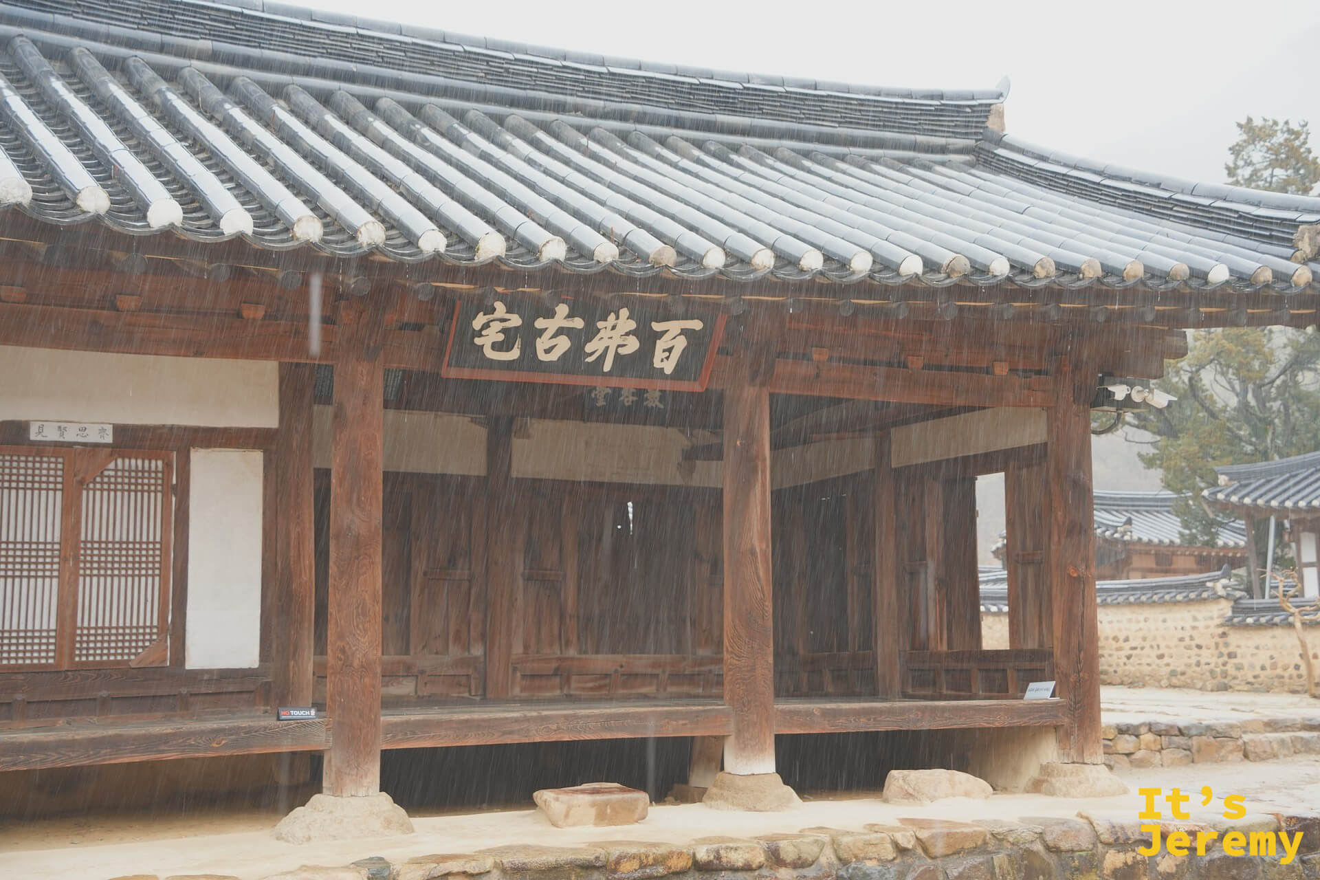 百弗古宅主廳，「百弗古宅」漢字大匾高掛正中，大雨傾盆而下，柱礎石浸在雨水裡