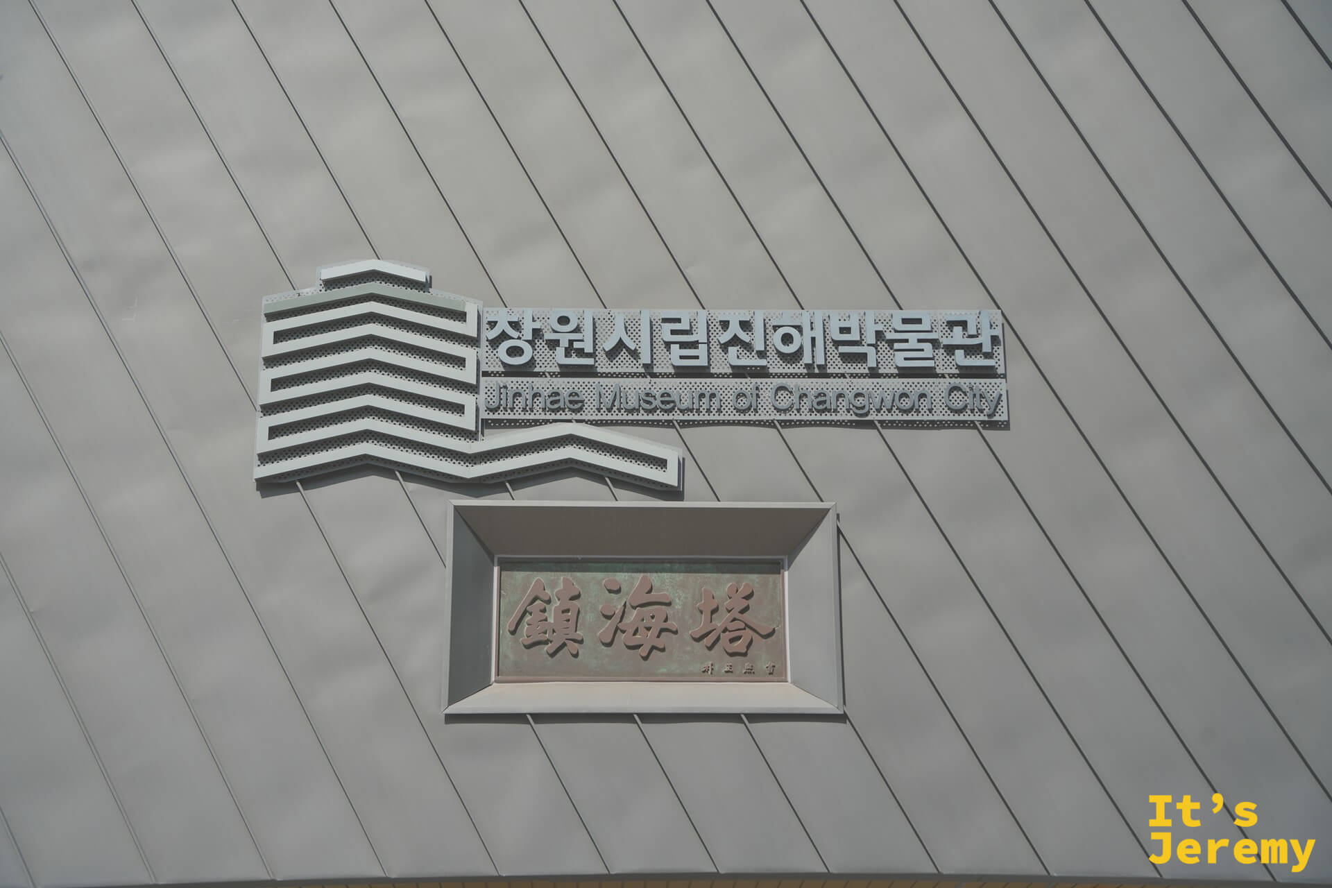 昌原市立鎮海博物館外牆,上方為博物館英韓文名稱,下方是刻著「鎮海塔」的銅色牌匾