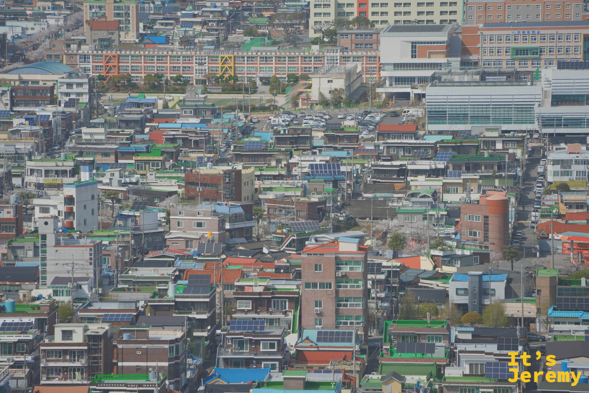 另一角度的城區鳥瞰,學校建築與居民樓彼此穿插,依稀可見日治時代棋盤規劃留下的街道痕跡