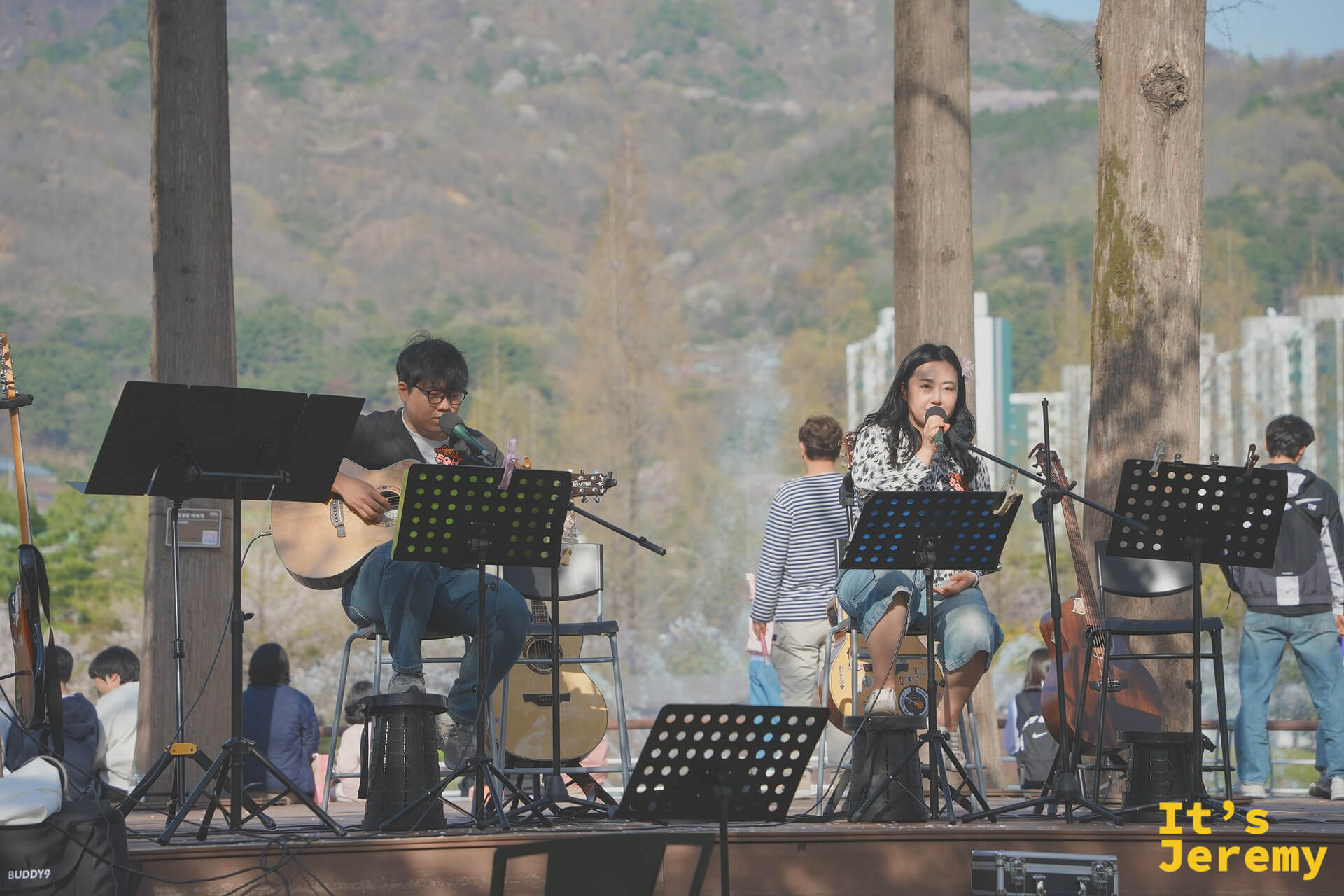 戶外表演台上樂團現場演出，山脈與城市天際線作為自然背景