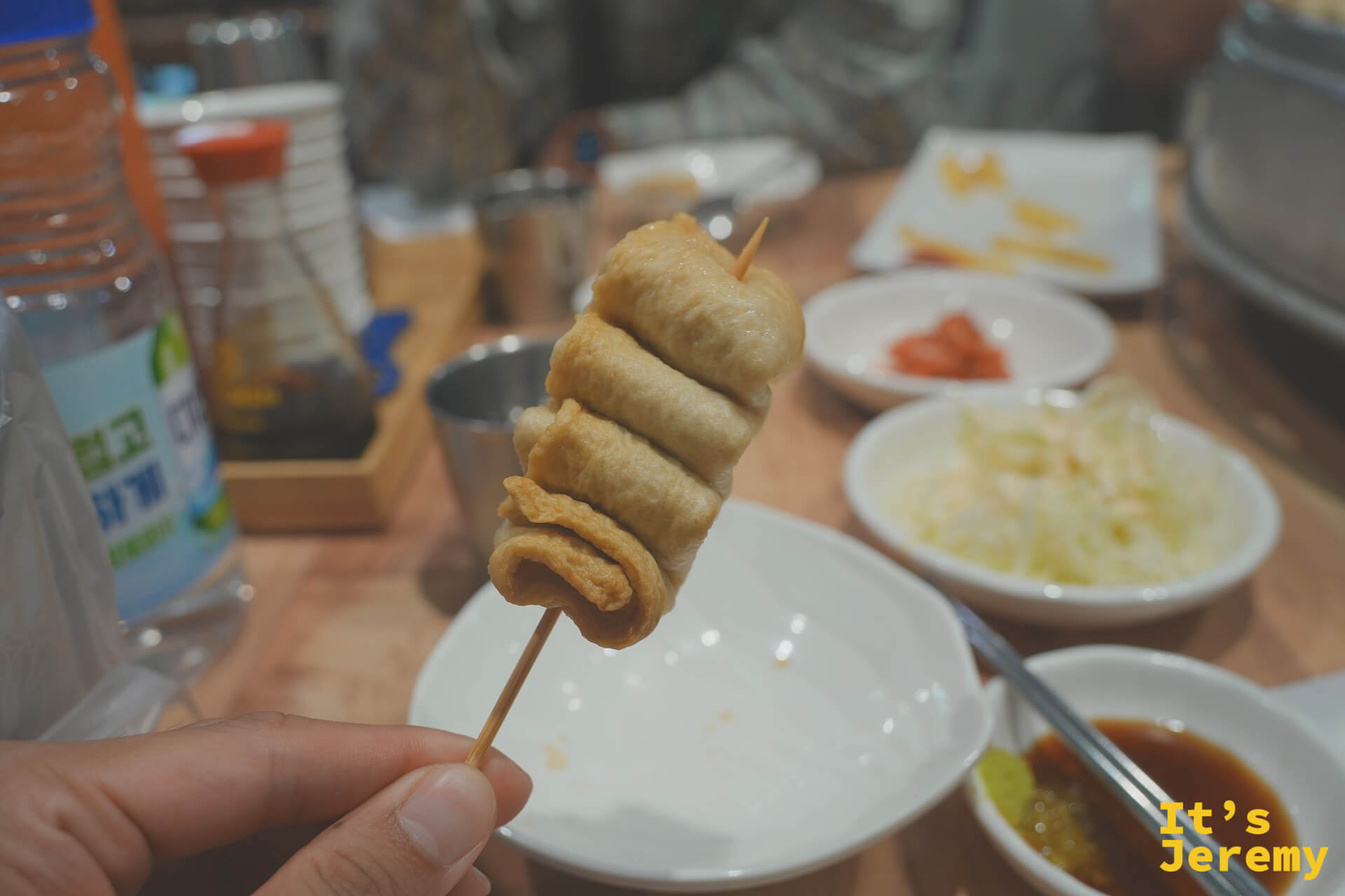 手持一根魚板串,準備沾取桌上的醬料