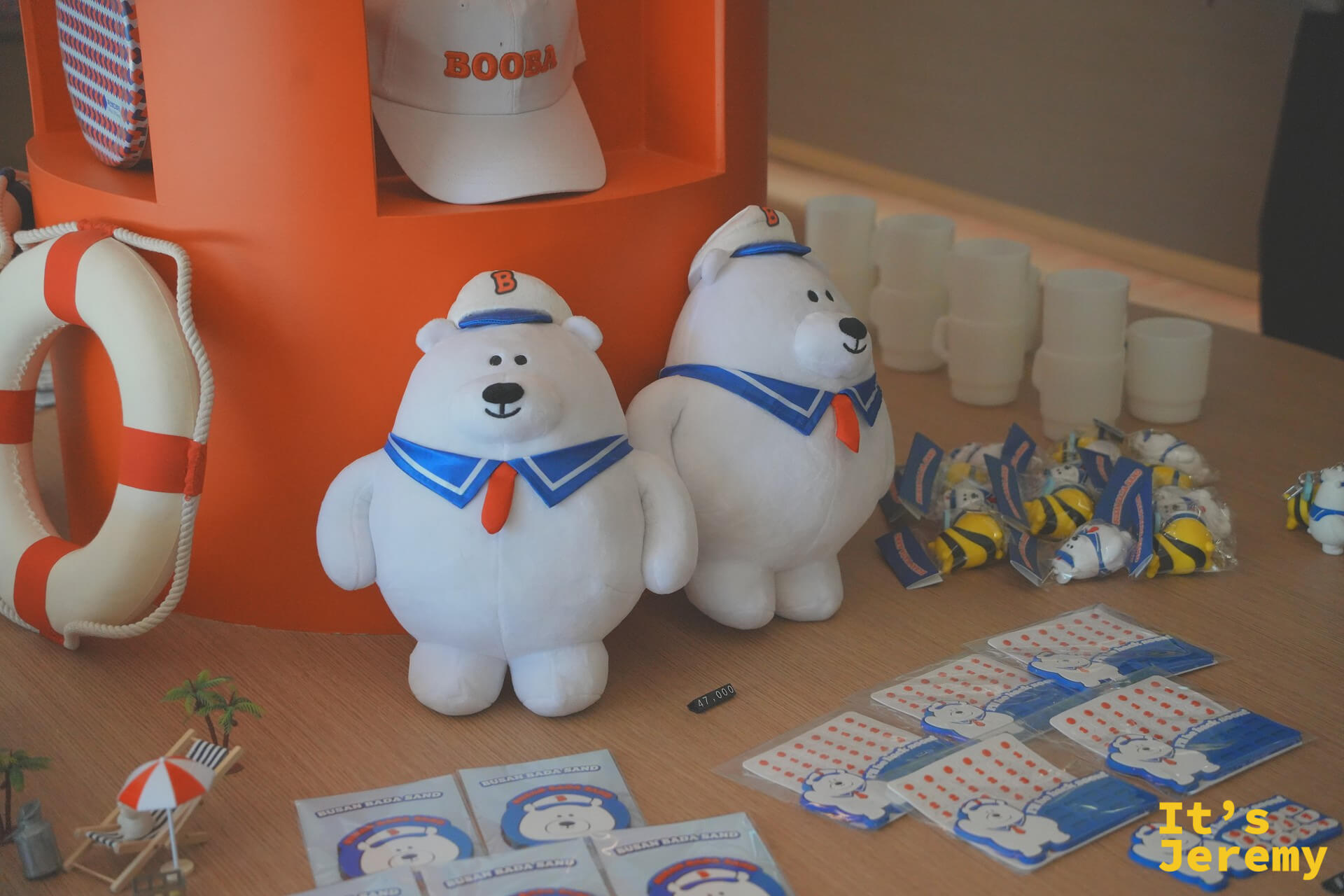 Busan Bada Sand 的品牌吉祥物 Booba——北極熊造型公仔系列,穿著水手服站在品牌展示台上,周邊商品從公仔到棒球帽一應俱全