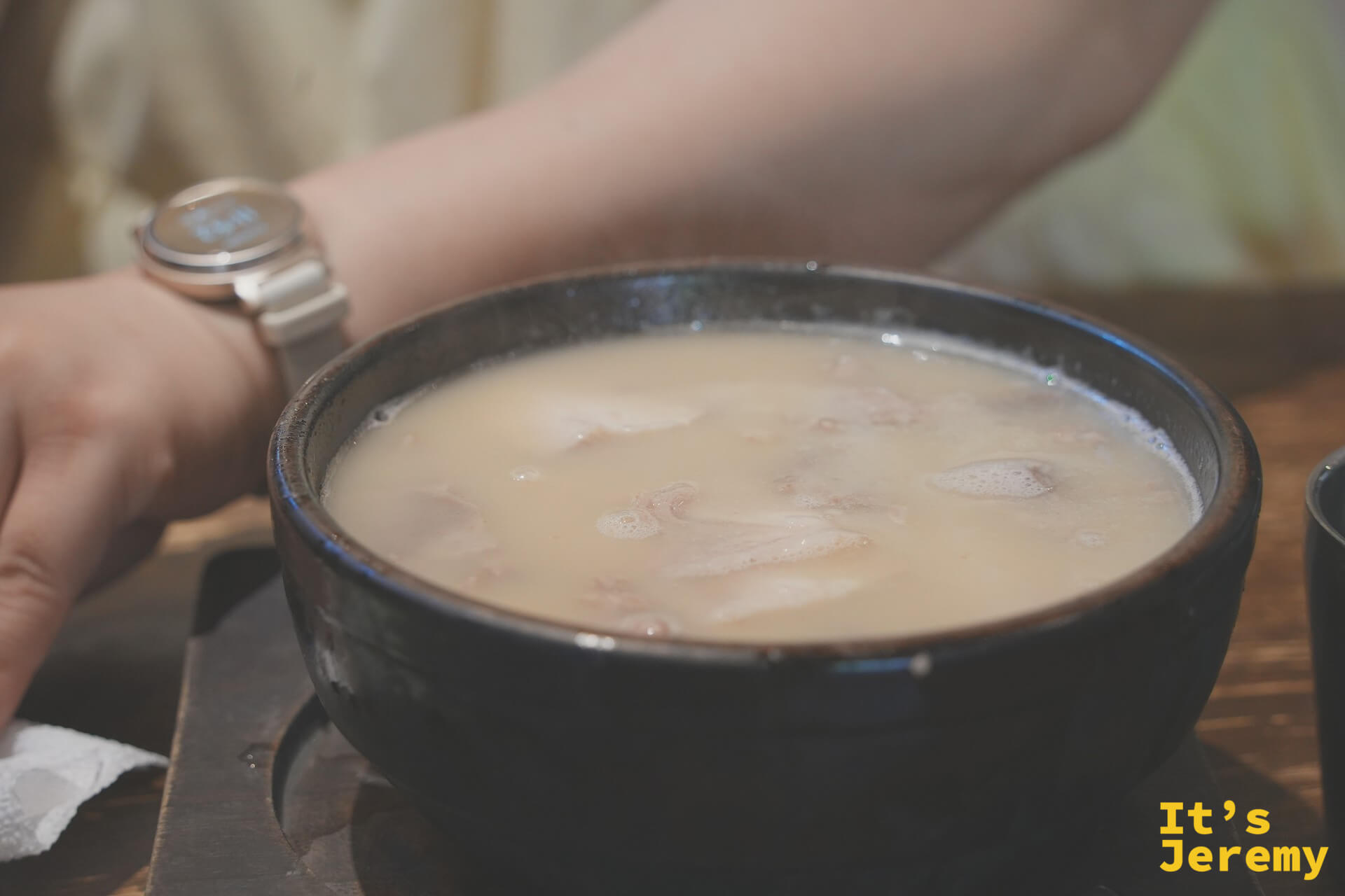 密陽式豬肉湯飯，湯色奶白濃厚，石鍋盛裝，蒸氣從湯面緩緩升起