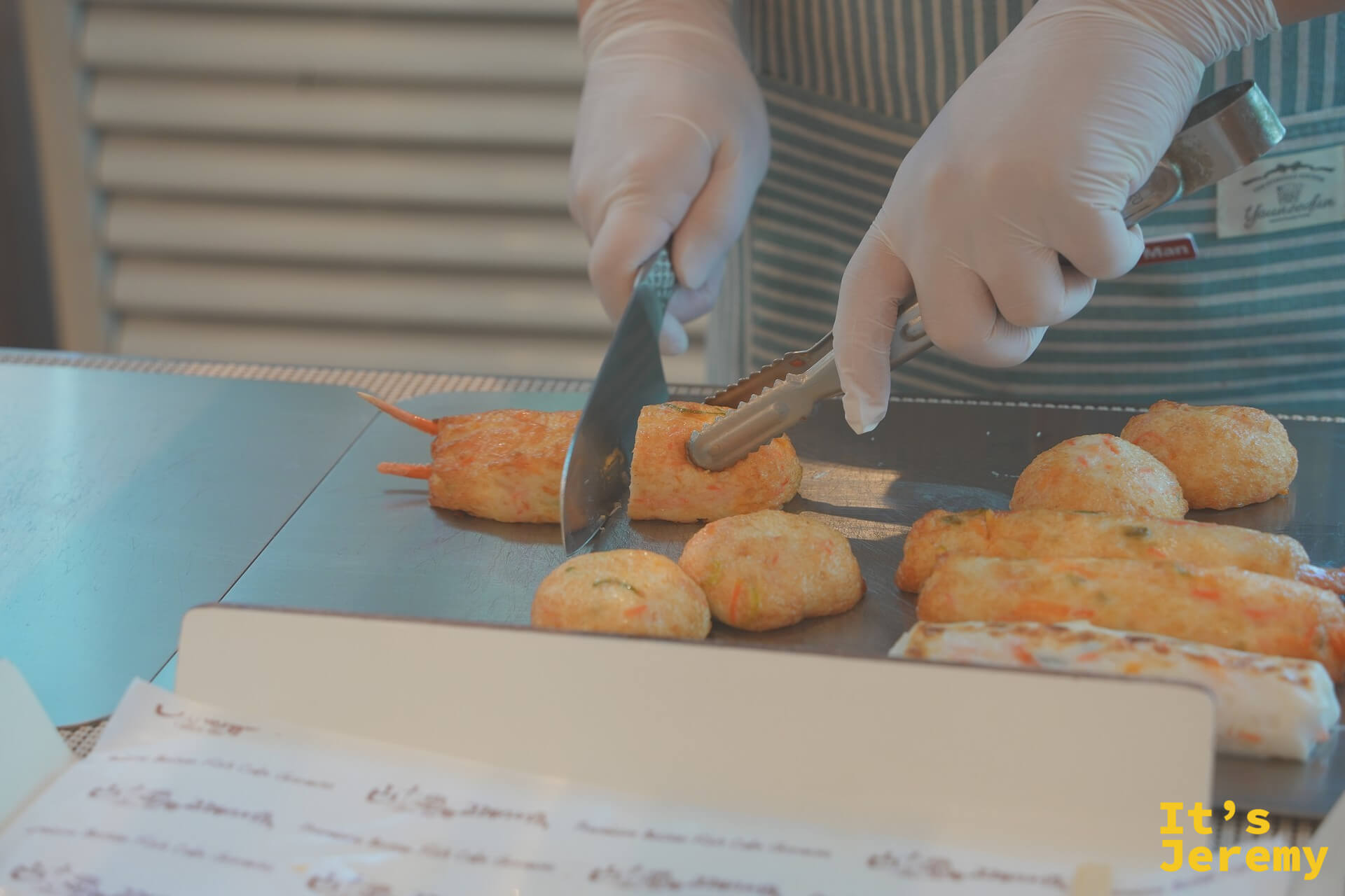 師傅用料理夾在操作台上翻動蝦仁魚板，準備進行切塊