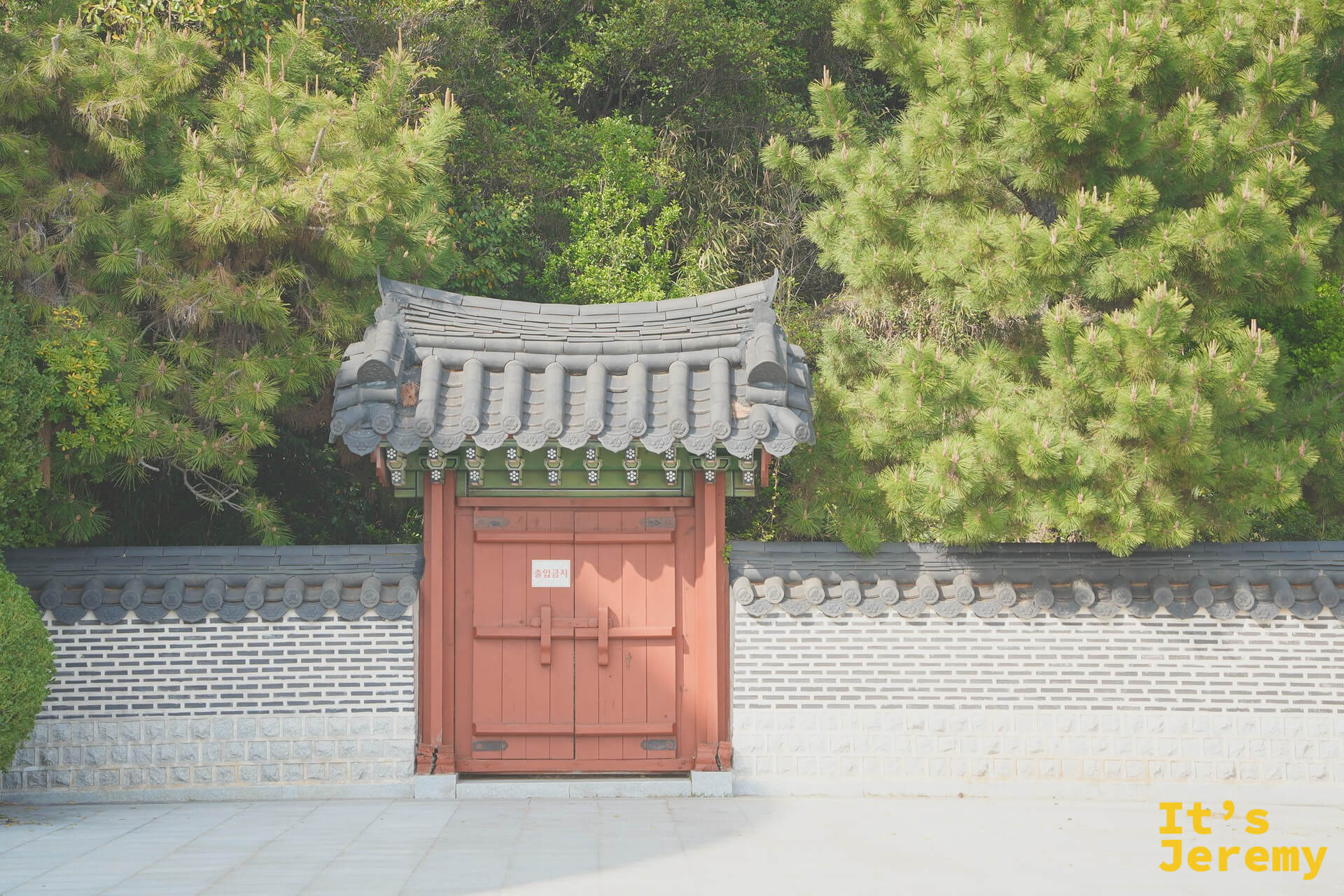 누리마루 APEC 하우스 傳統韓式入口大門，紅色木門搭配灰磚圍牆，兩側松林環繞
