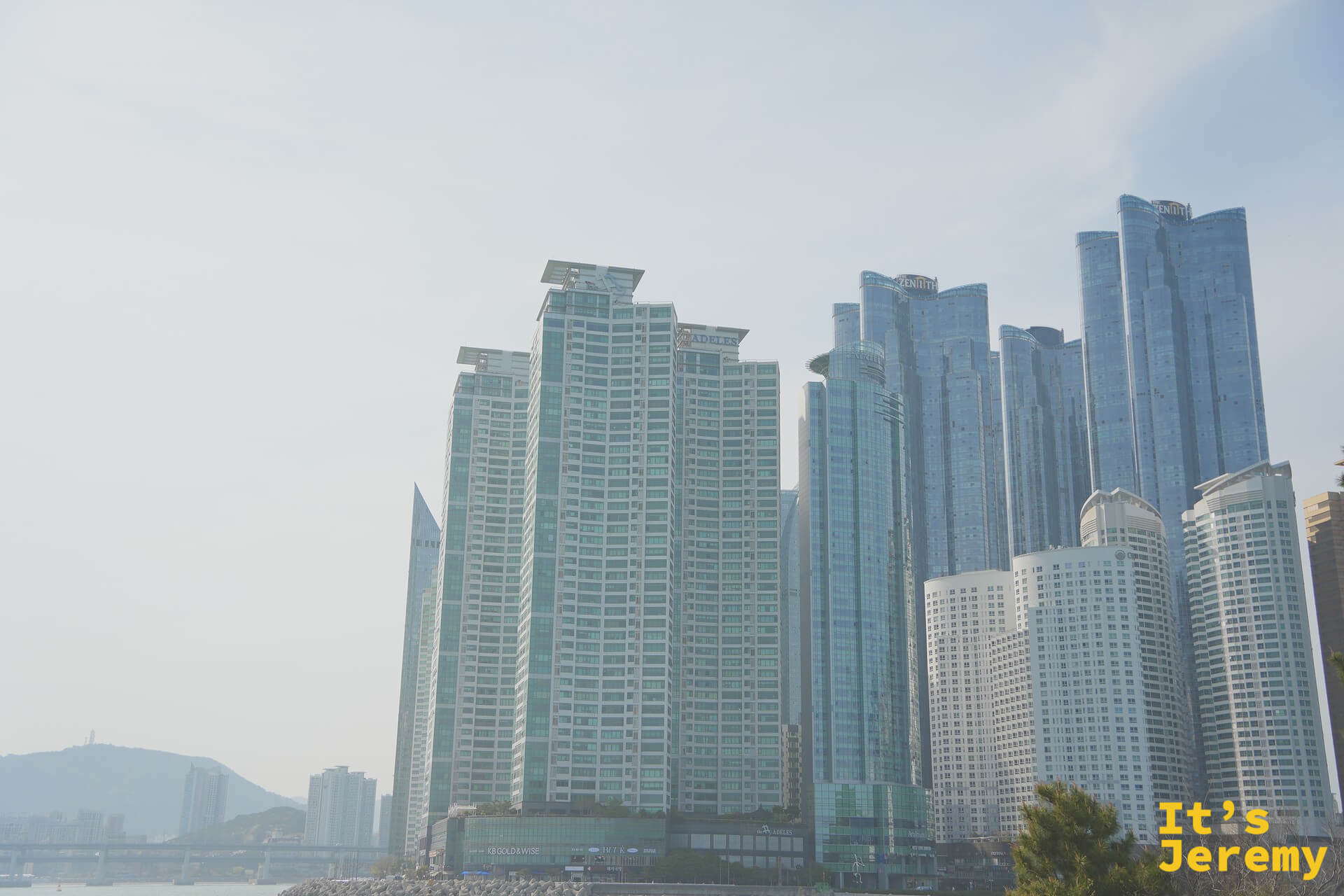 從冬柏島眺望釜山海雲臺 Marine City 密集的玻璃帷幕高樓群，與步道的礁石自然形成強烈對比