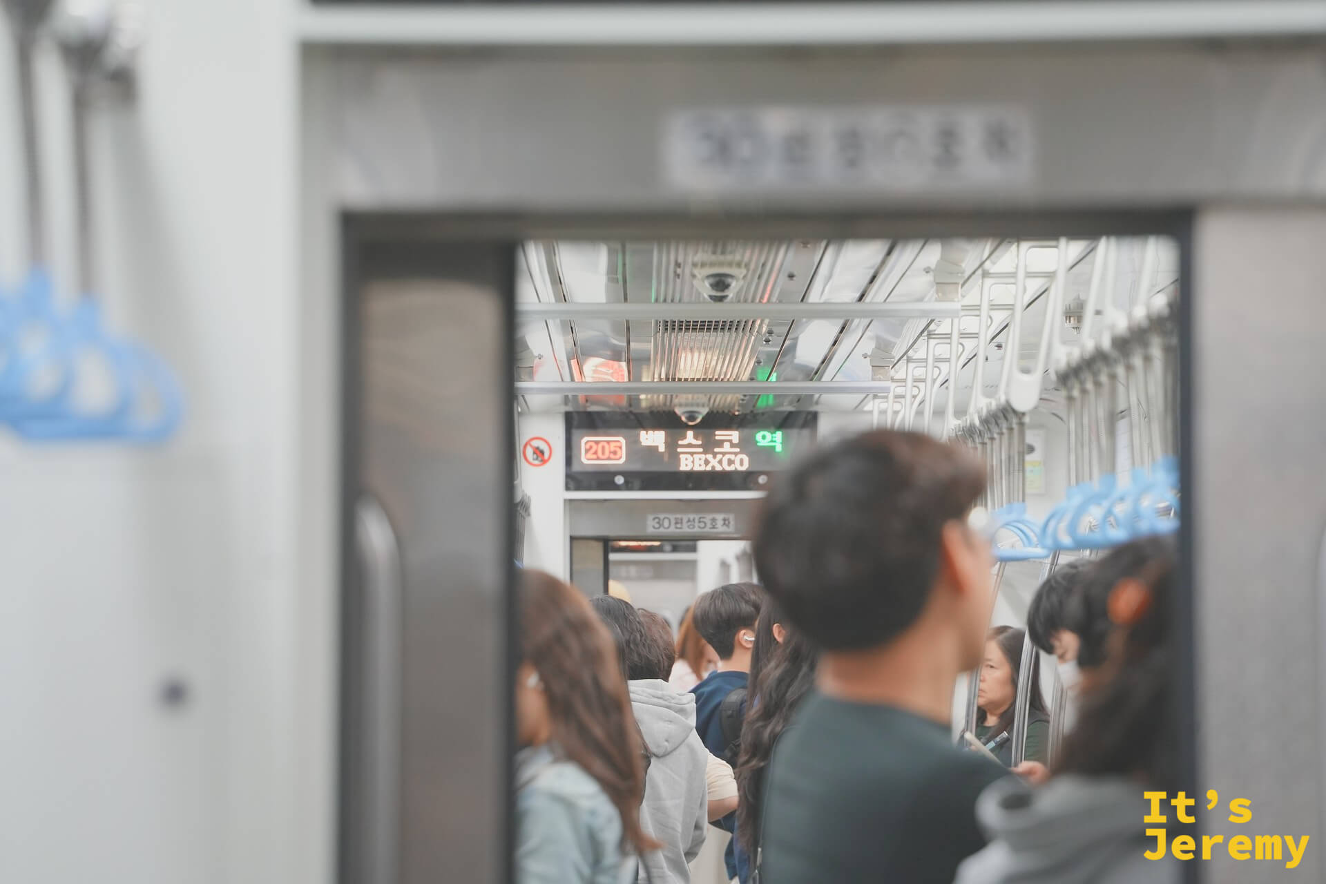 地鐵 2 號線車廂內,頭頂顯示板亮著「벡스코 역 BEXCO」——車廂裡站滿週末出遊的人潮,再過幾站就是廣安里