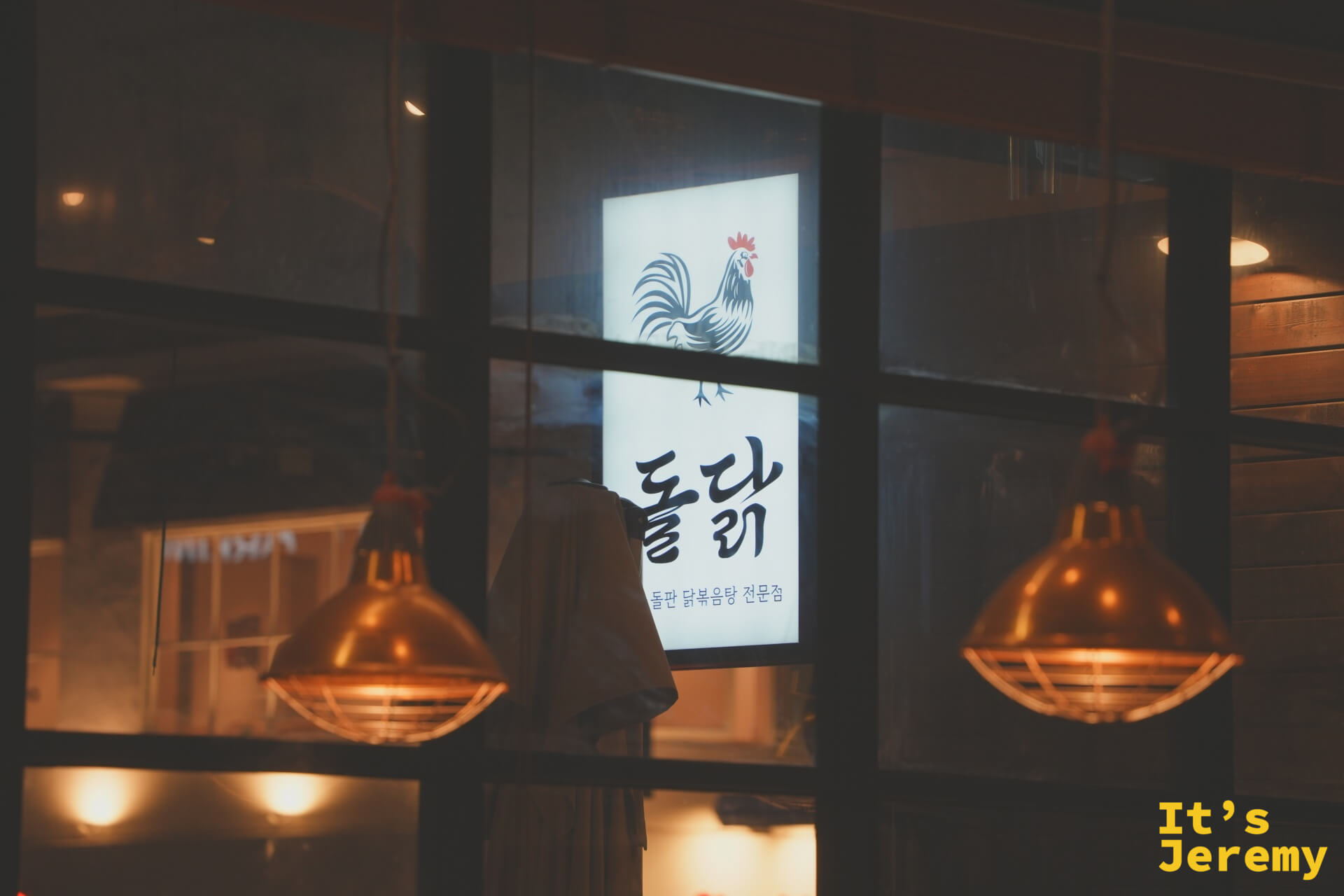 入夜後的돌닭門面,銅燈打出暖光,玻璃窗映出公雞招牌,氛圍感滿分