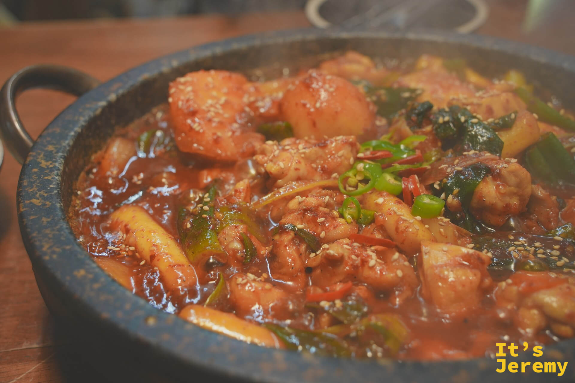石板辣炒雞上桌,醬汁濃稠、芝麻點綴,鍋裡還在冒煙