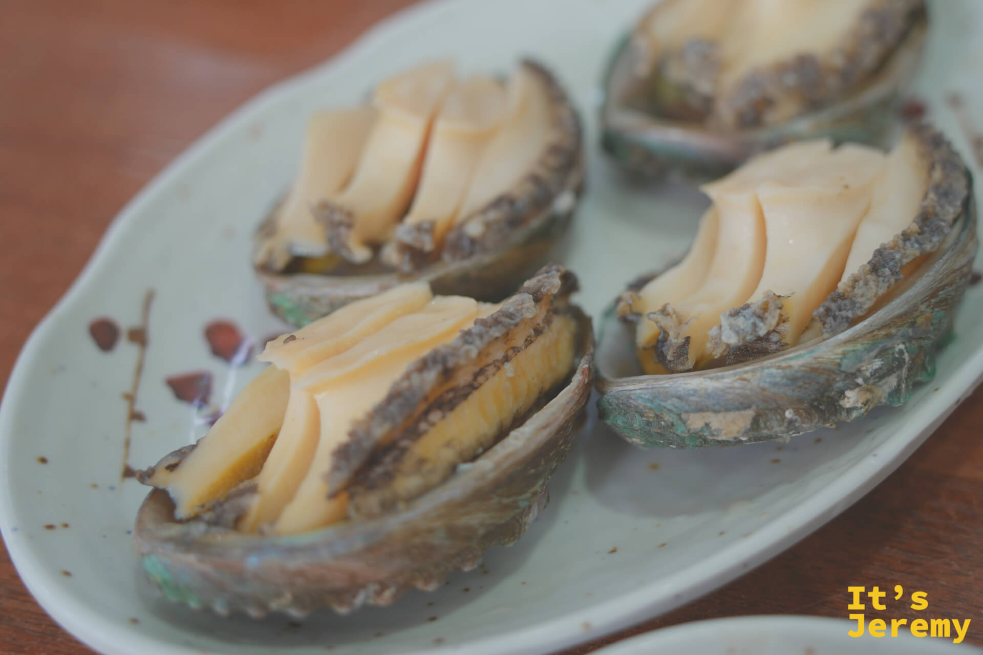찐전복蒸鮑魚:四個鮑魚帶殼上桌,刀切開後呈扇形展開,蒸出的汁液在殼內留著