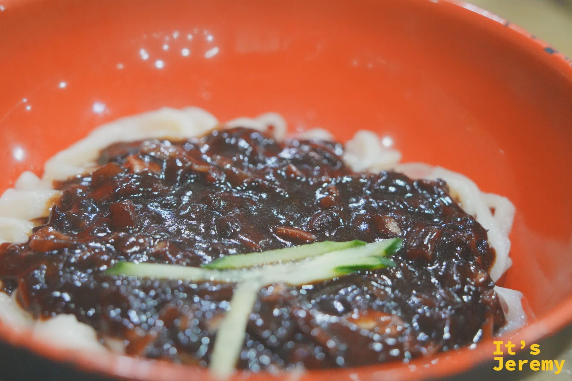 橘紅大碗裡的짜장면,漆黑豆醬厚覆在手切麵條上,點綴兩根黃瓜絲