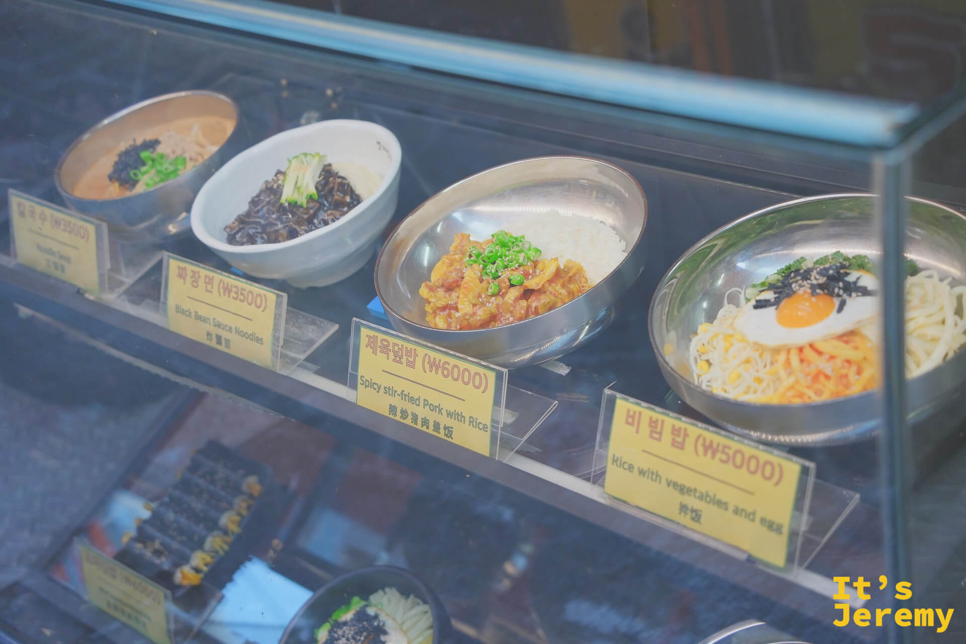 門口展示櫃的食物模型,清楚標示品項名稱與售價,中英日文對照