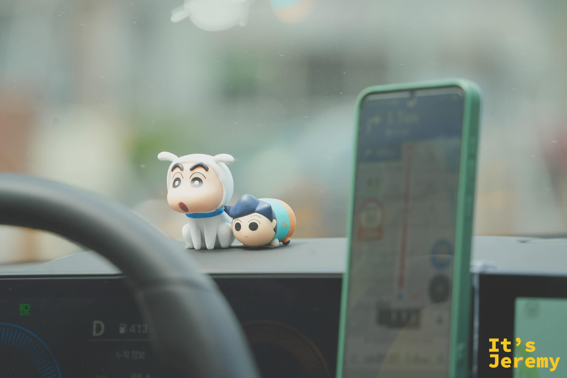 Kakao Taxi 儀表板上的蠟筆小新公仔與另一隻小人偶，旁邊是導航手機架