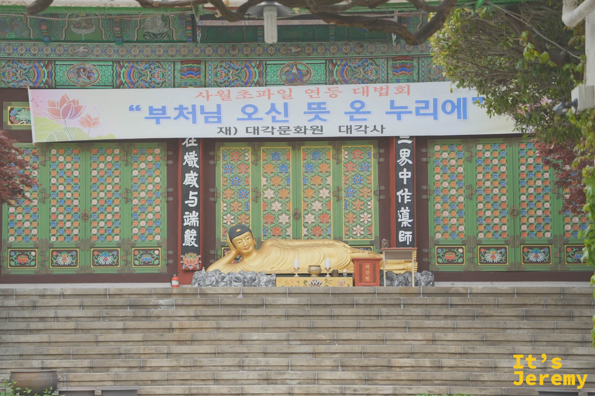 南浦洞路邊的大覺寺臥佛，彩繪木構建築前橫著佛誕節慶標語
