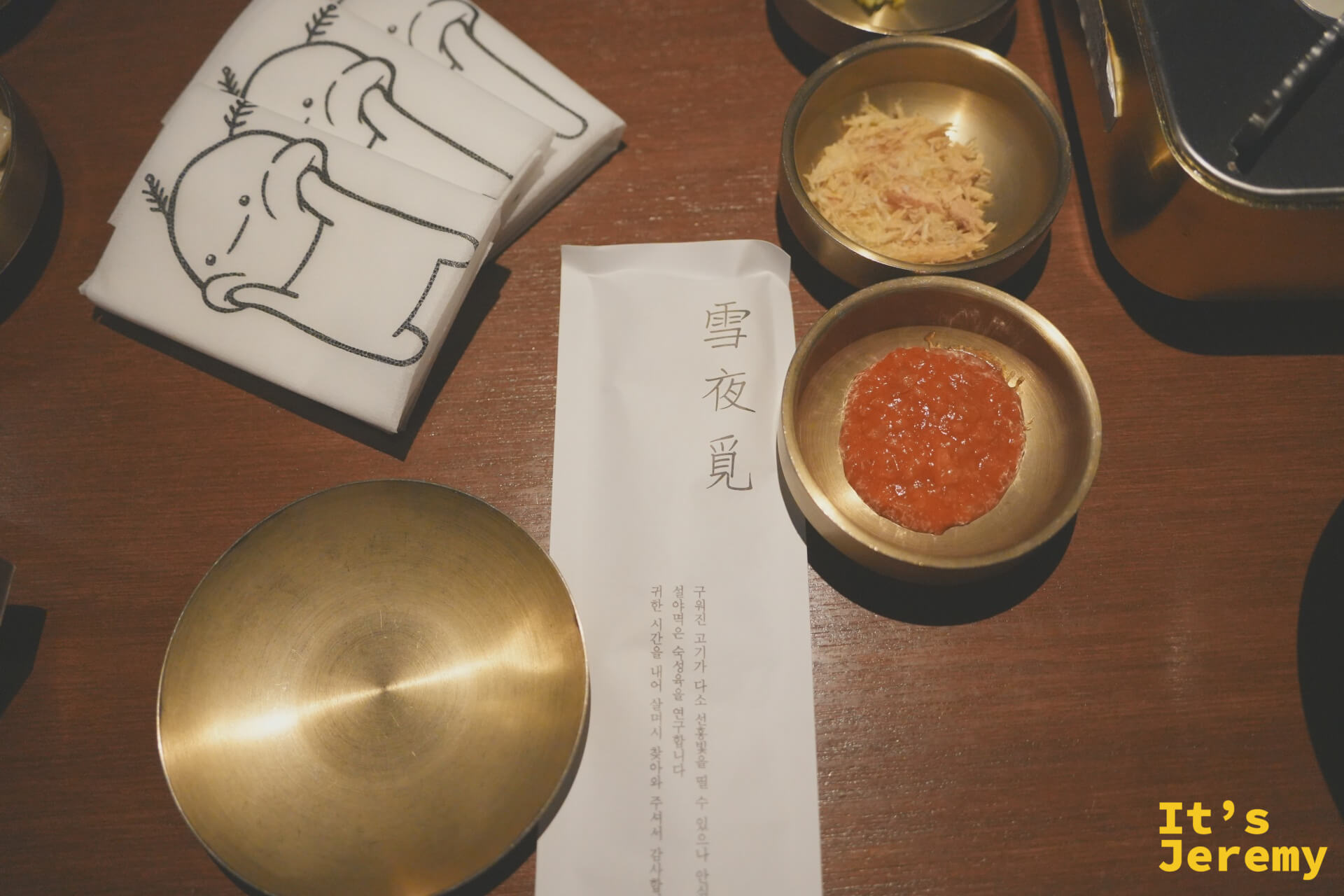 入座時桌上的雪夜覓菜單牌與黃銅配料小碗，鮭魚卵紅得誘人