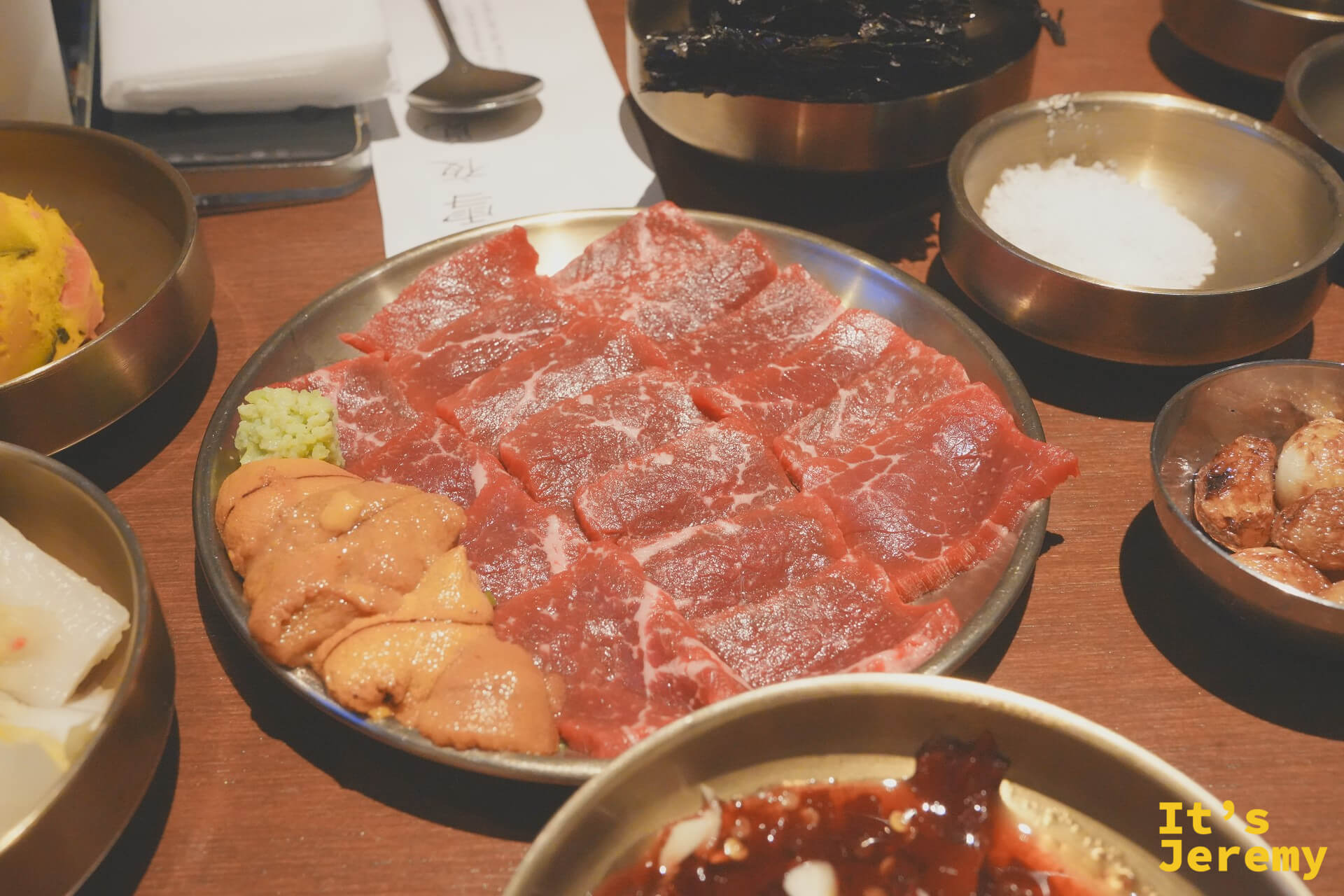 端上桌的韓牛生肉組合，油花豐富的낙엽살板腱肉鋪滿整盤，旁邊搭著海膽