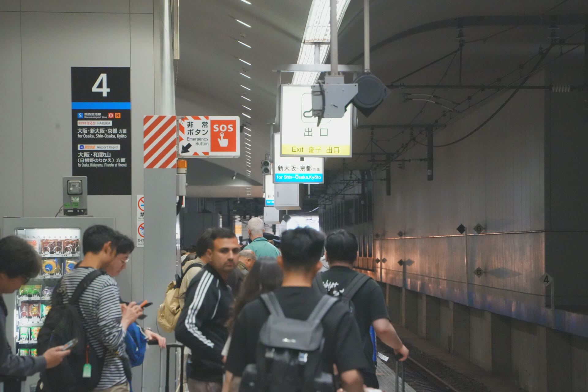 關西空港 4 番ホーム月台，旅客拎著行李等候，指示牌標示「新大阪・京都」方向