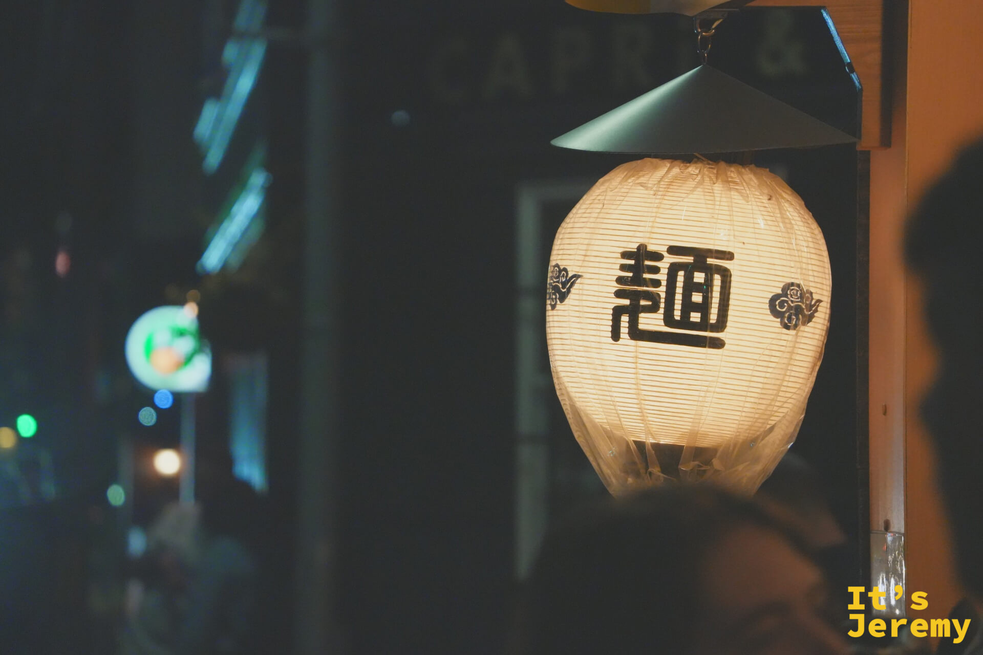 入夜的巷弄，寫著「麺」字的燈籠在黑暗中亮起