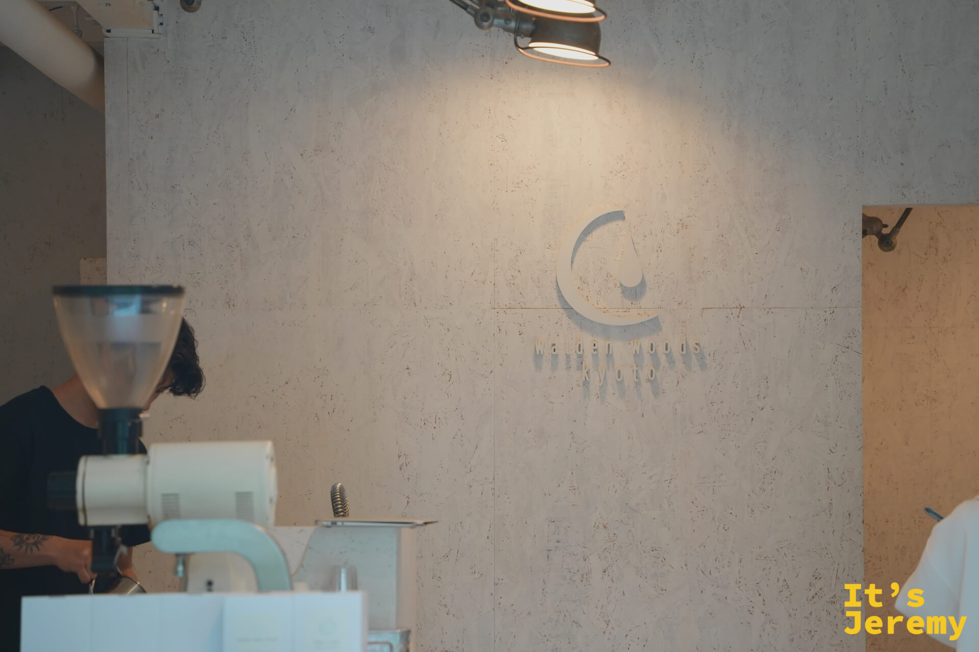 Walden Woods Kyoto logo 牆，烘豆師在一旁專注工作