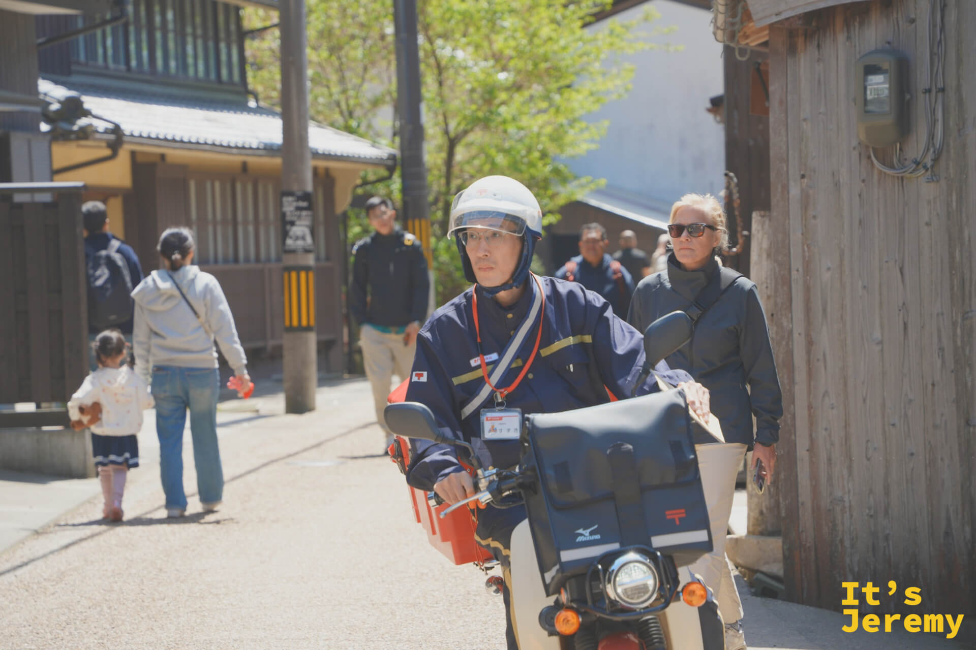 郵便配達員が伊根の路地をバイクで走る