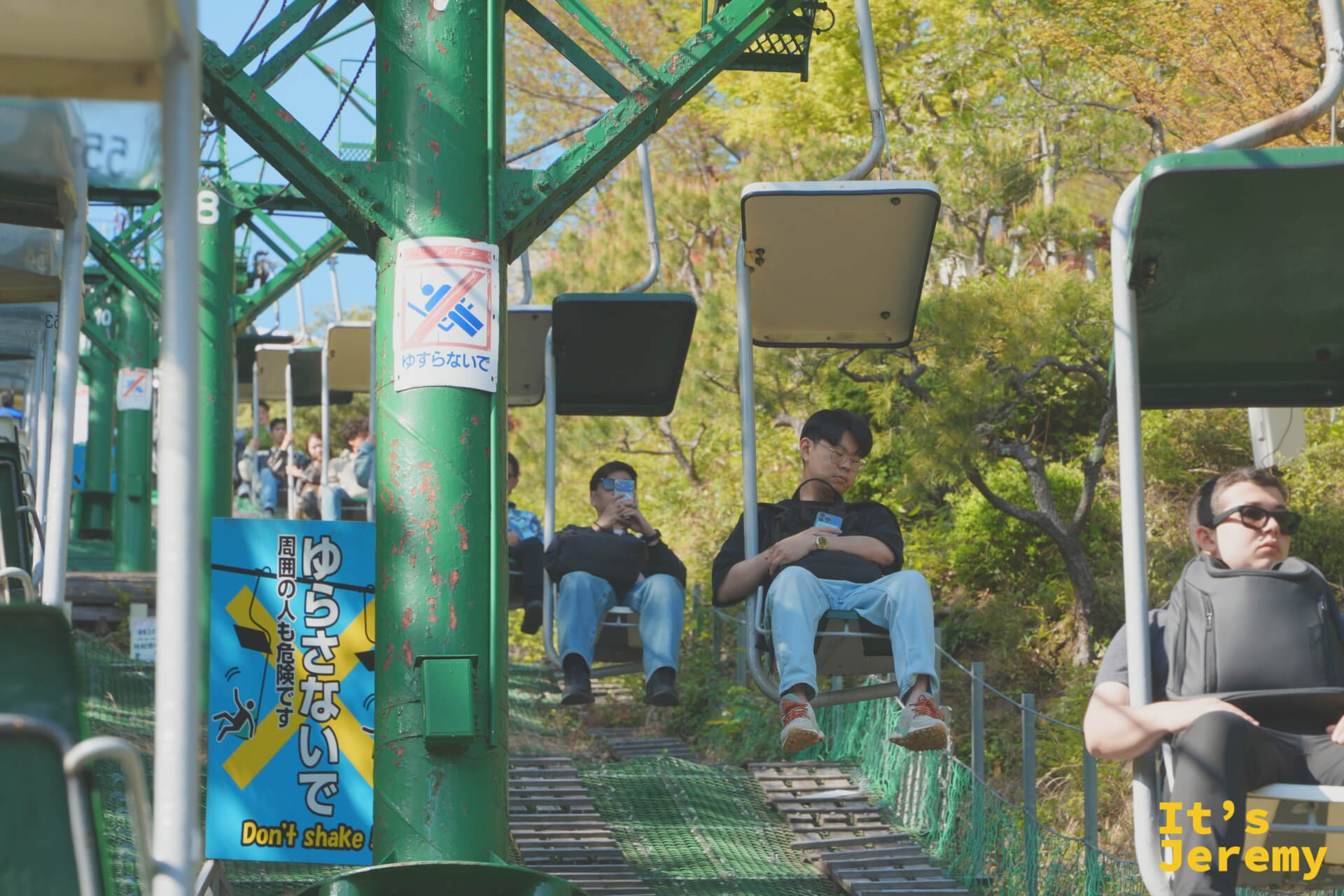 リフトに乗る人々と「ゆらさないでください」の看板