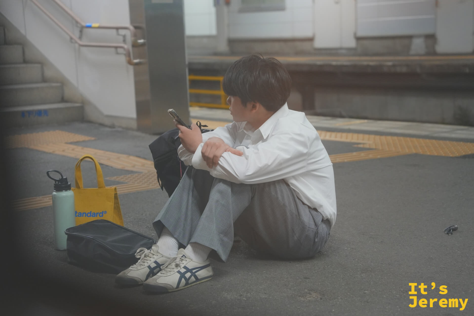 月台の床に座って待つ同行者