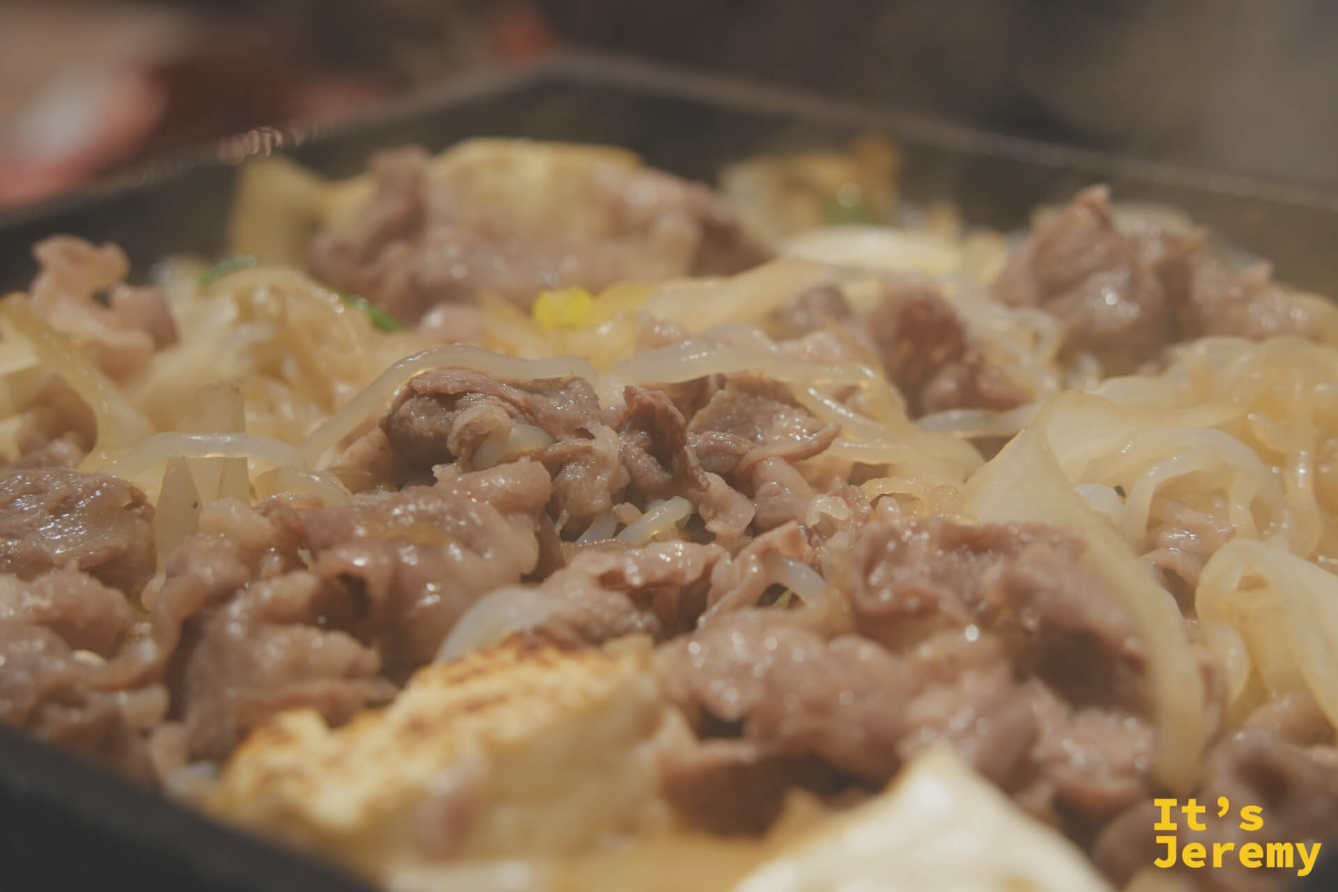 壽喜燒在鐵鍋中滋滋作響，牛肉與洋蔥同煮