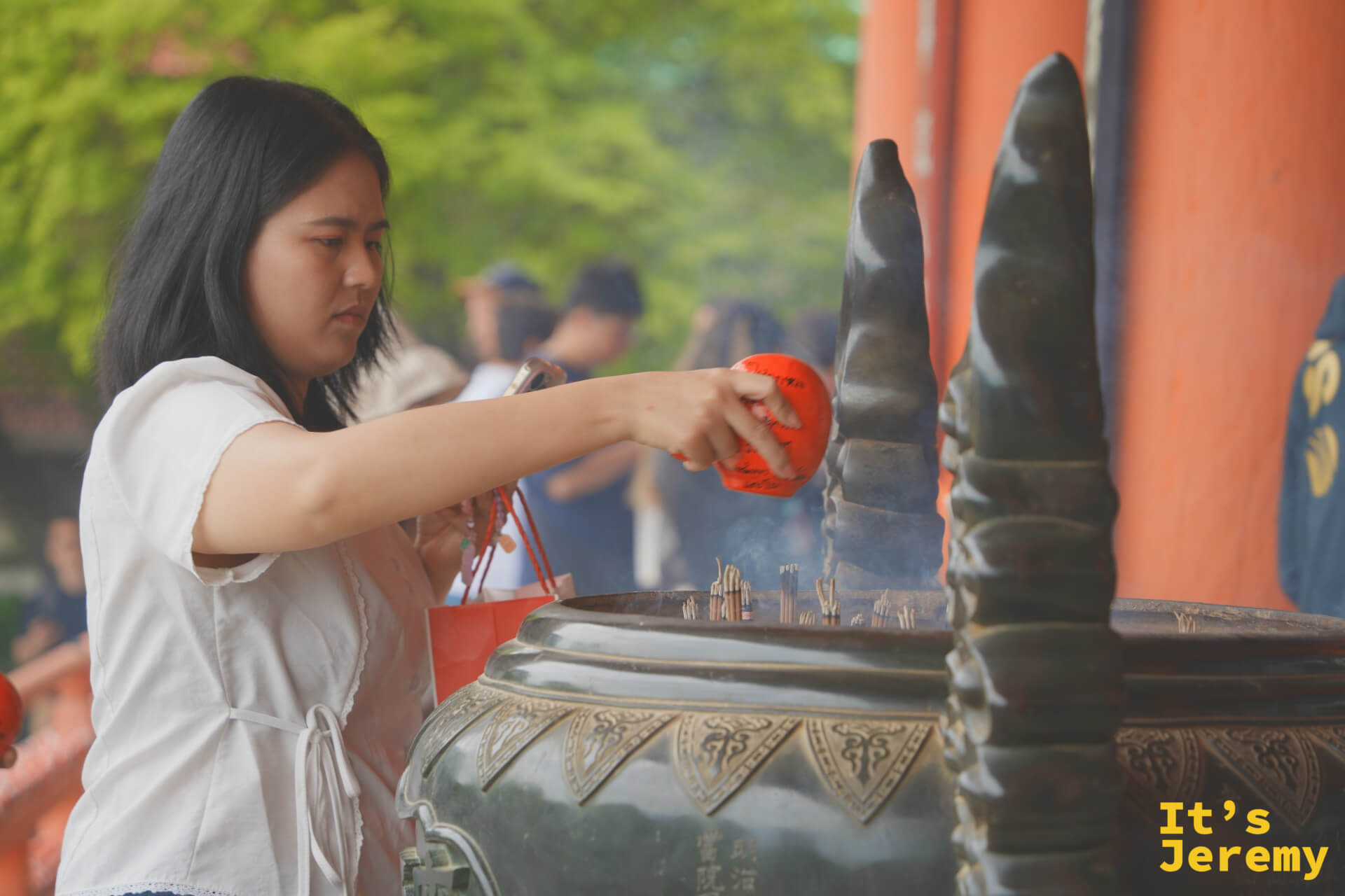 女性拿著小達摩靠近香爐,讓煙霧繚繞達摩