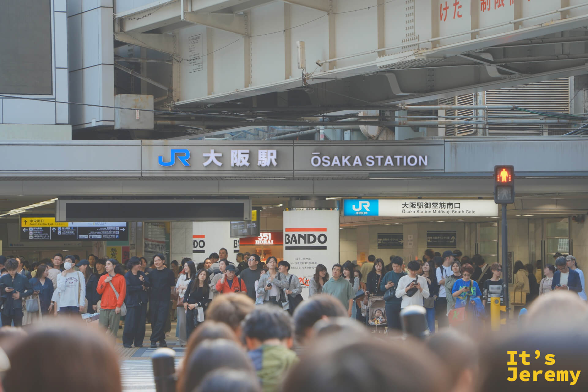 JR 大阪駅御堂筋南口站前，等紅燈的人群背後是整排站牌，大阪駅四個字直接掛在正面