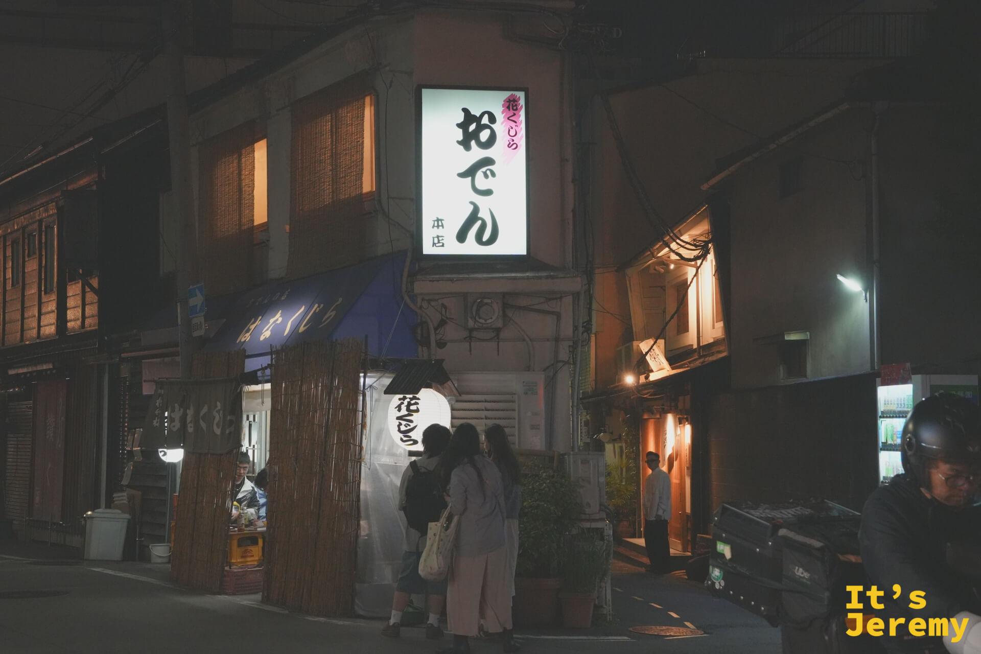 花くじら 本店外觀，入夜後おでん燈箱亮起，旁邊是竹籬笆圍起的等候區