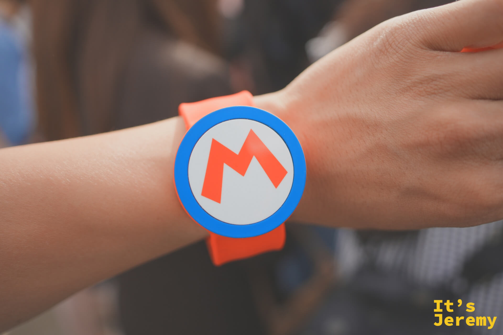 Mario Power-Up Band 手環，圓形設計搭配 M 字 LOGO，橘色腕帶非常顯眼