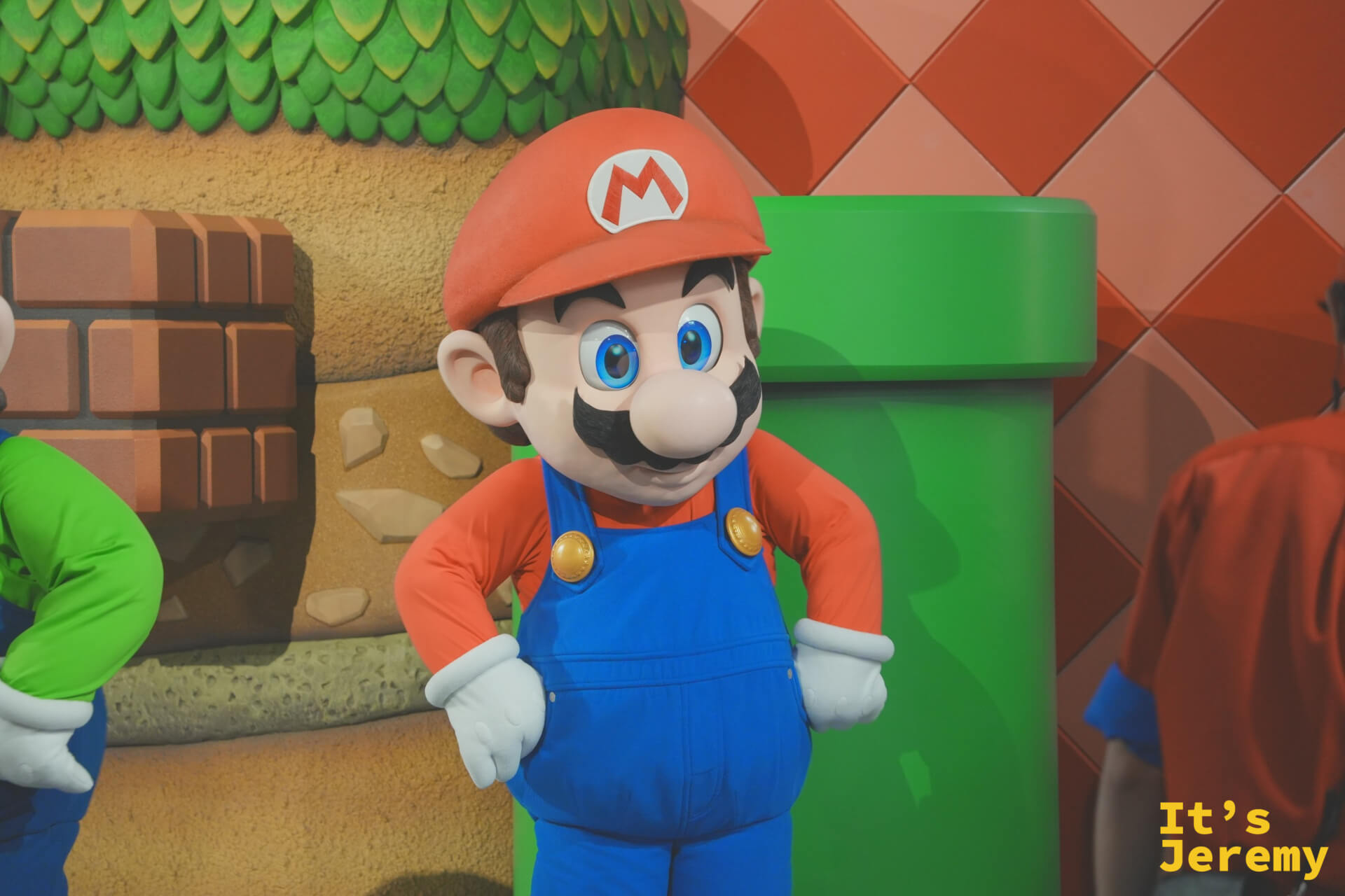 Mario 本人出現了！與遊客互動的 Mario 角色，面對鏡頭時眼神充滿活力，綠色水管背景配色剛好