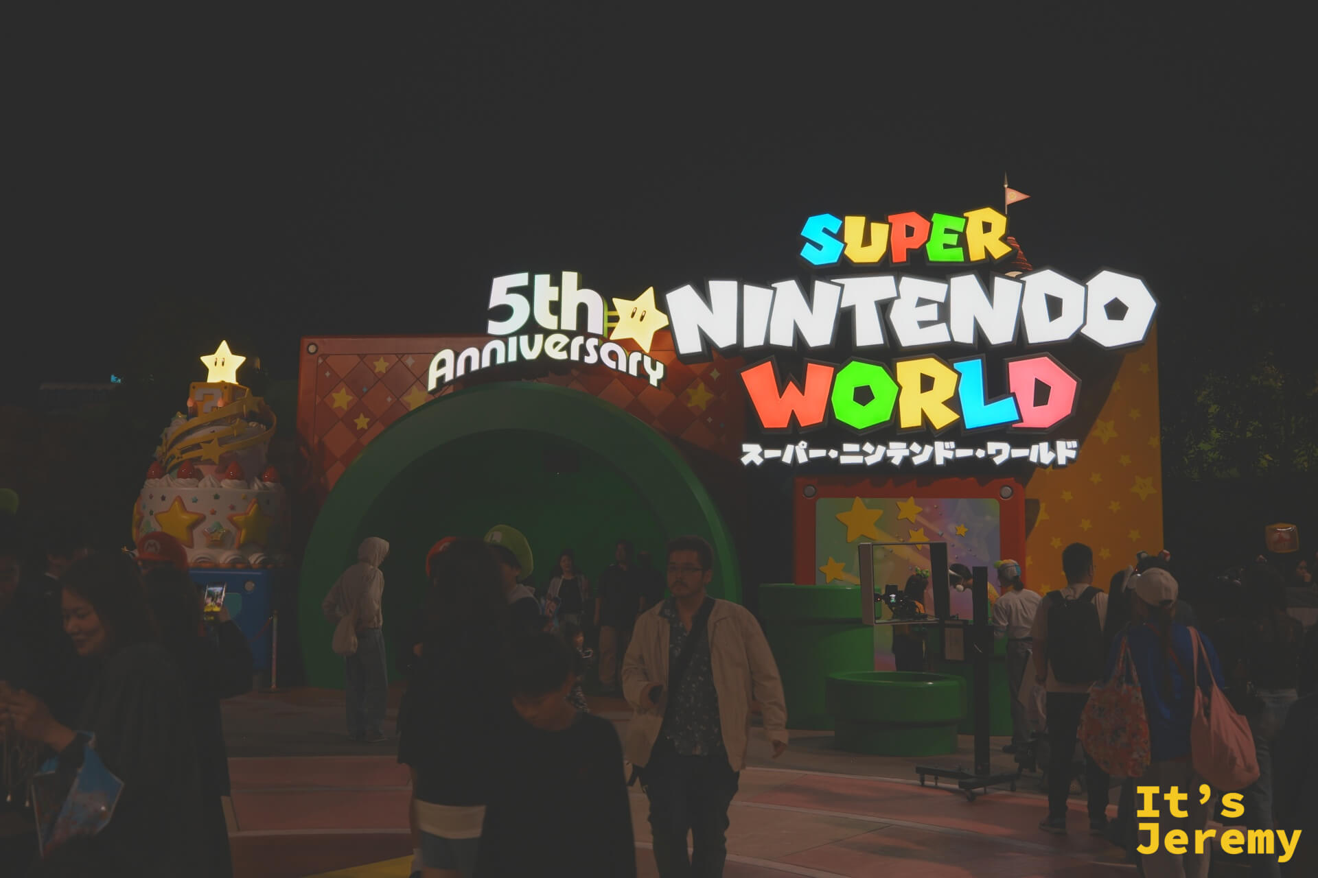 入夜後的超級任天堂世界入口，5th Anniversary 標誌與 Super Nintendo World 的彩色字體在黑夜中格外醒目