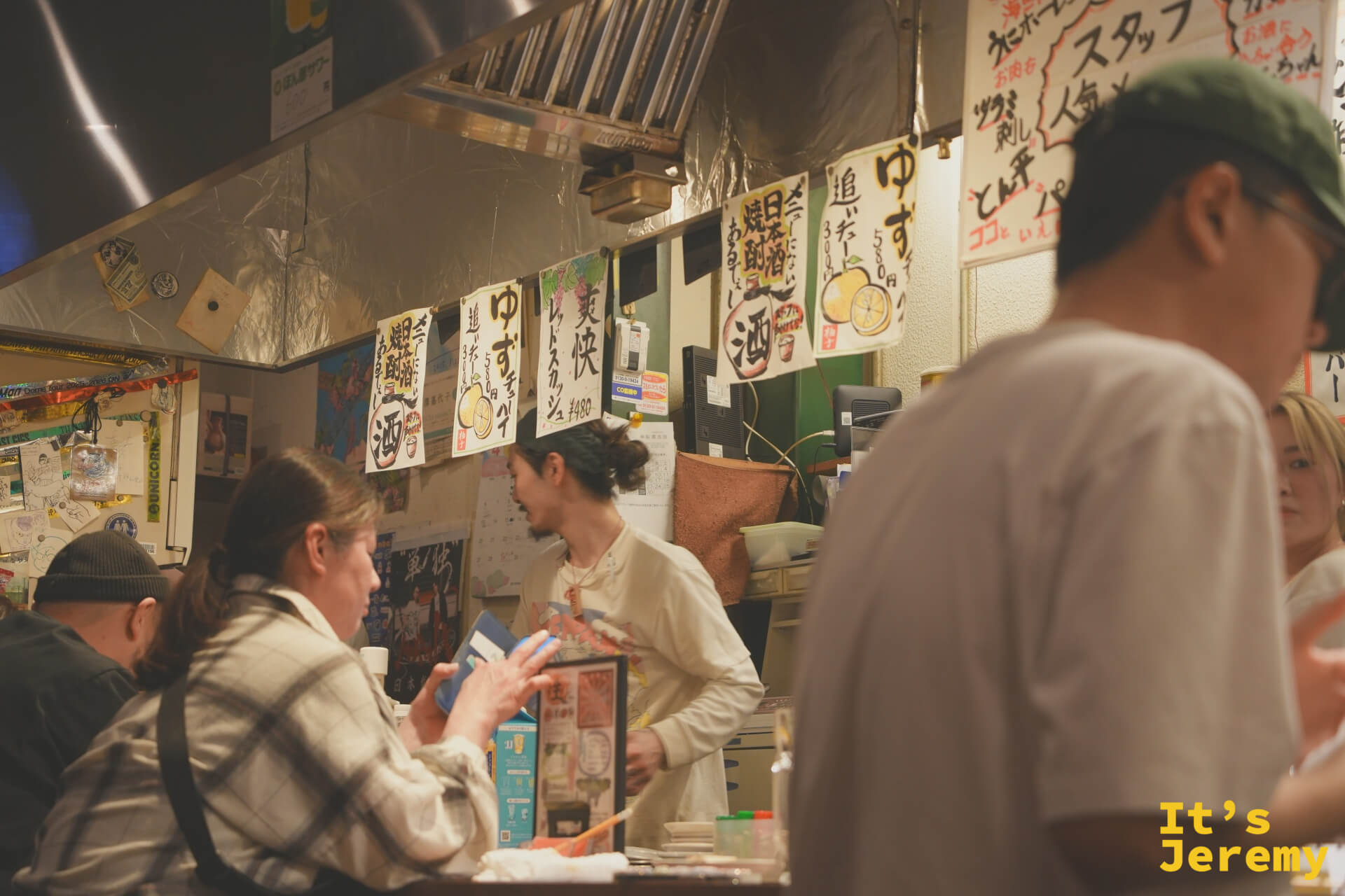 熱鬧的吧台座位區，客人與店員的距離極近，牆上掛著手寫柚子酒招牌
