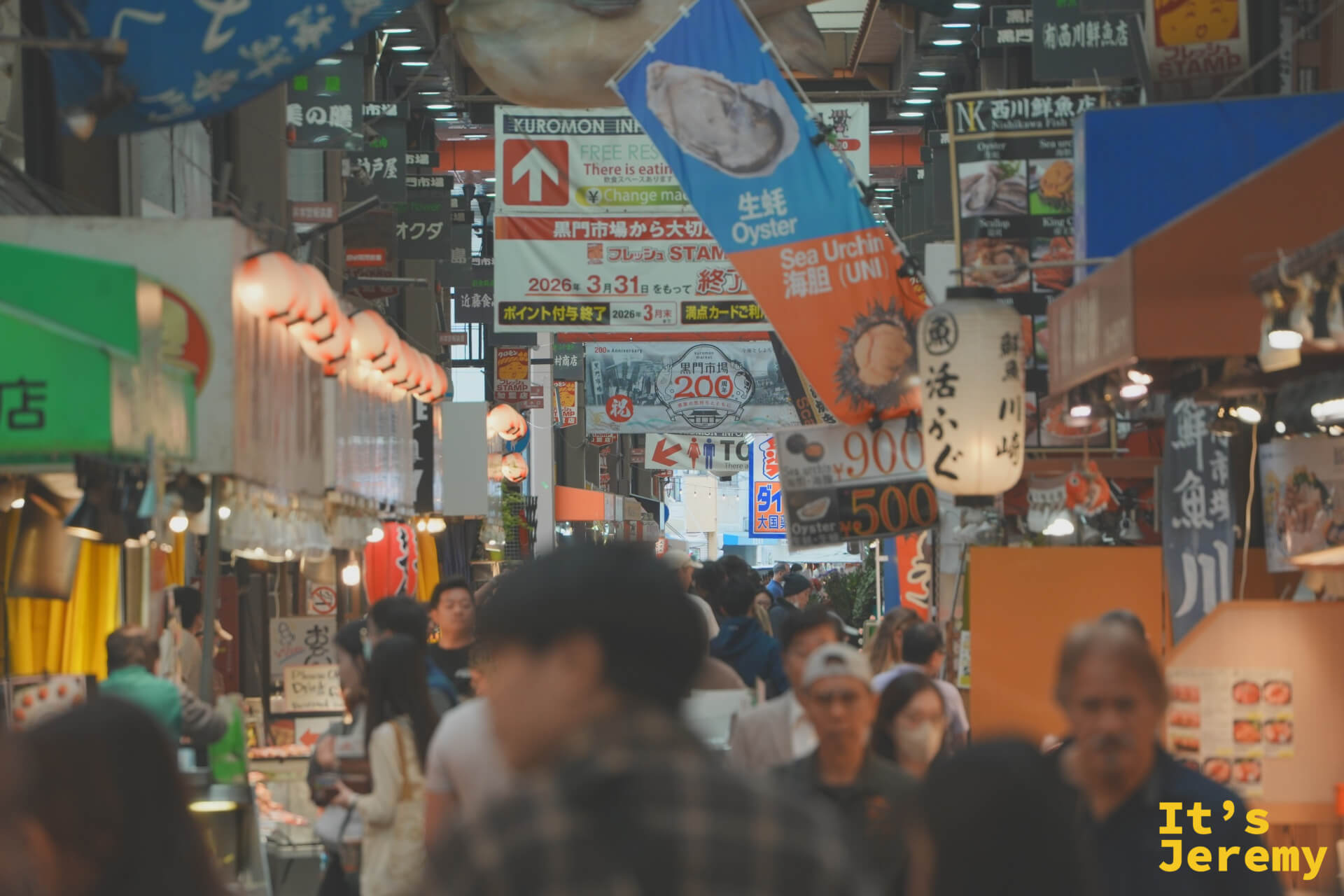 市場中段最熱鬧的地帶，牡蠣與海膽廣告旗幟高掛頭頂