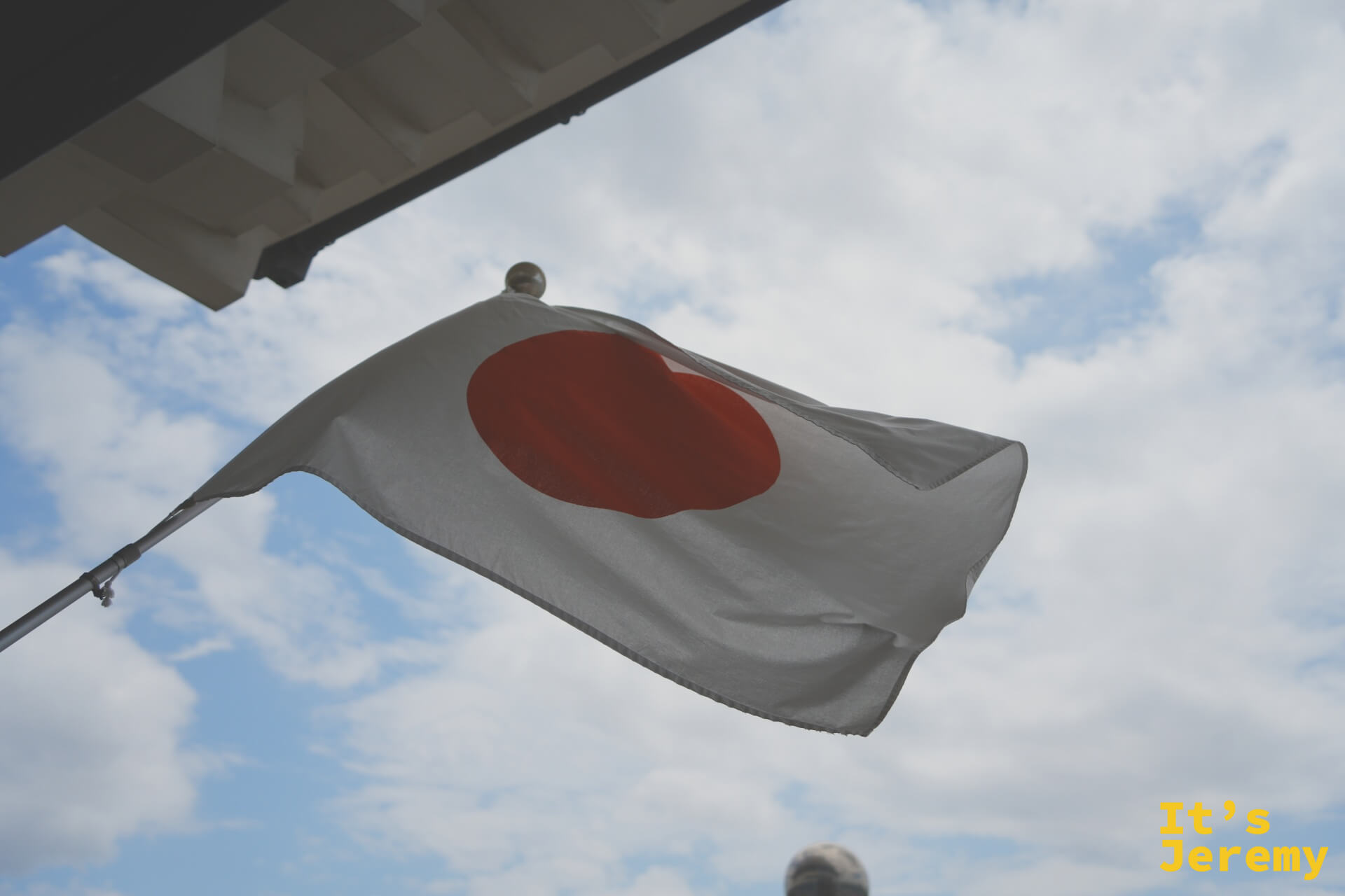 天守閣下方懸掛的日本國旗，仰角拍攝映著藍天